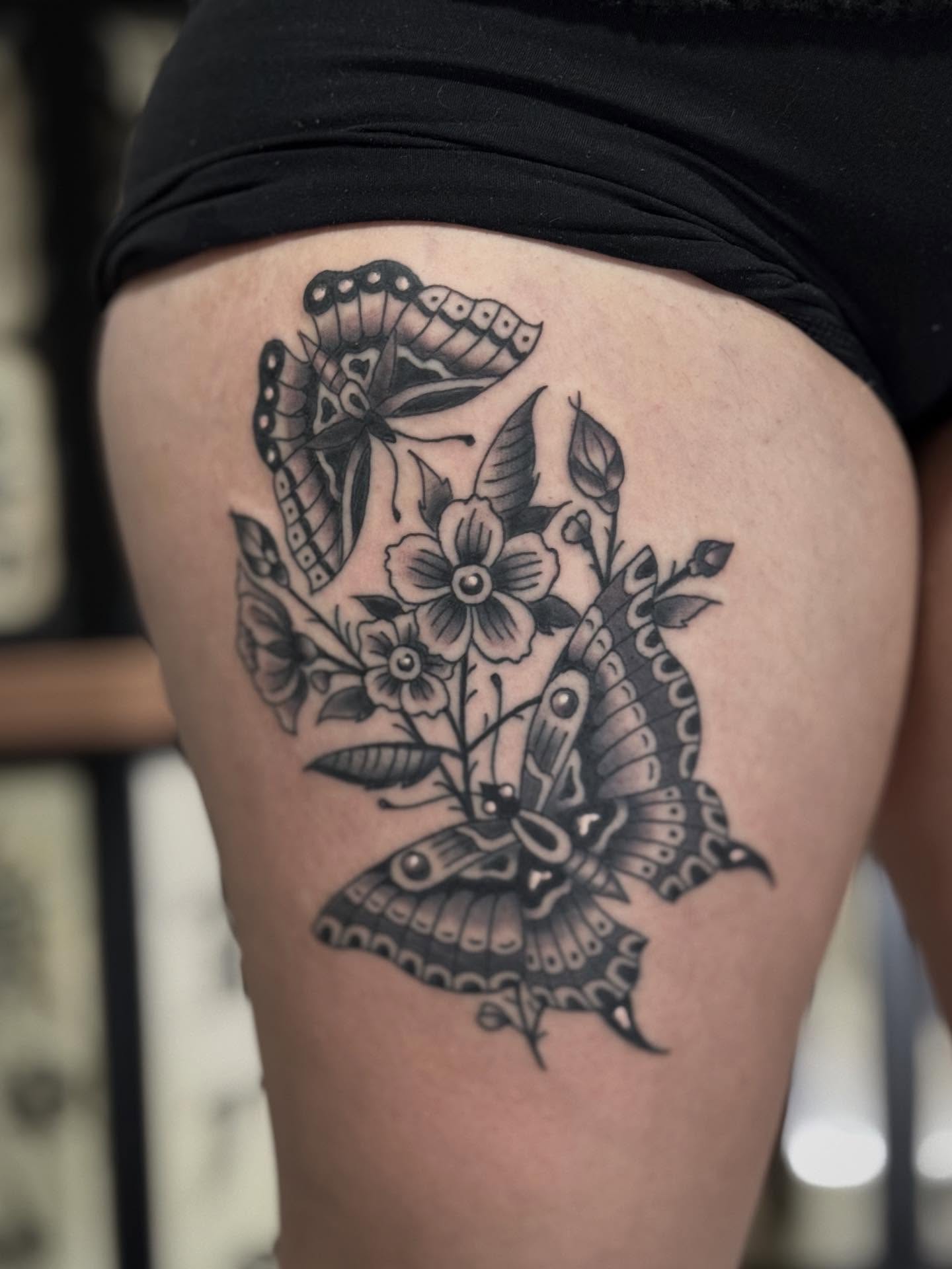 Butterflies and flowers black and grey tattoo on the thigh by Micah Norman, San Francisco, California