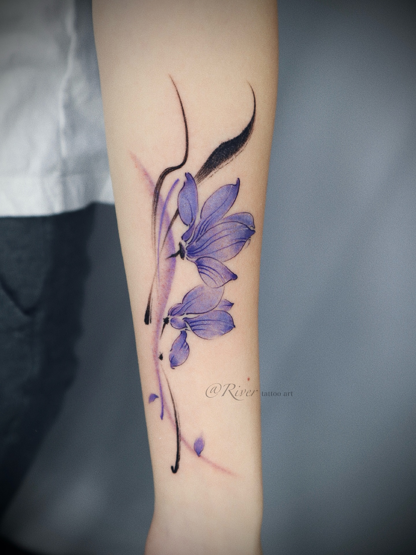 Purple flowers watercolor tattoo on the forearm by River