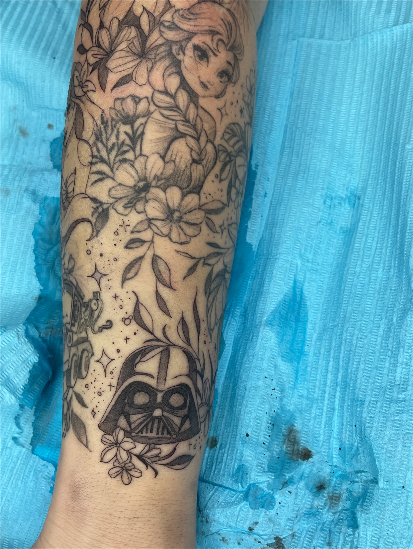 Frozen character and flowers black and grey tattoo on the forearm by Melissa Rose Moya