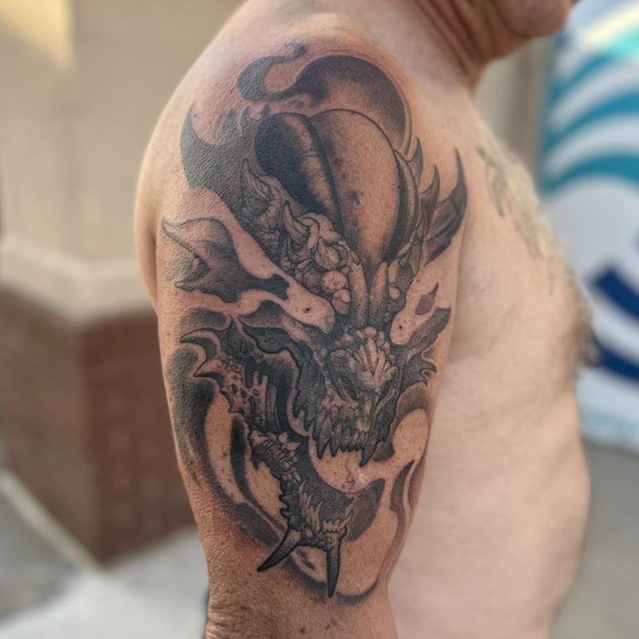 Dragon black and grey tattoo on the shoulder by Tattoos by Aeron Herald Maurbjorn, Sioux