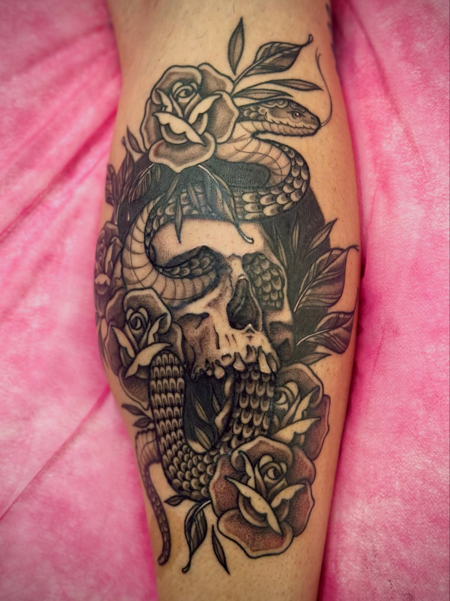 Skull with roses and snake American traditional tattoo on the forearm by Maddie Morrill