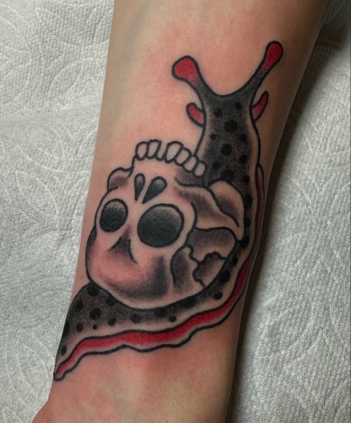 Skull and slug American traditional tattoo on the forearm by Daniel Skillingstead