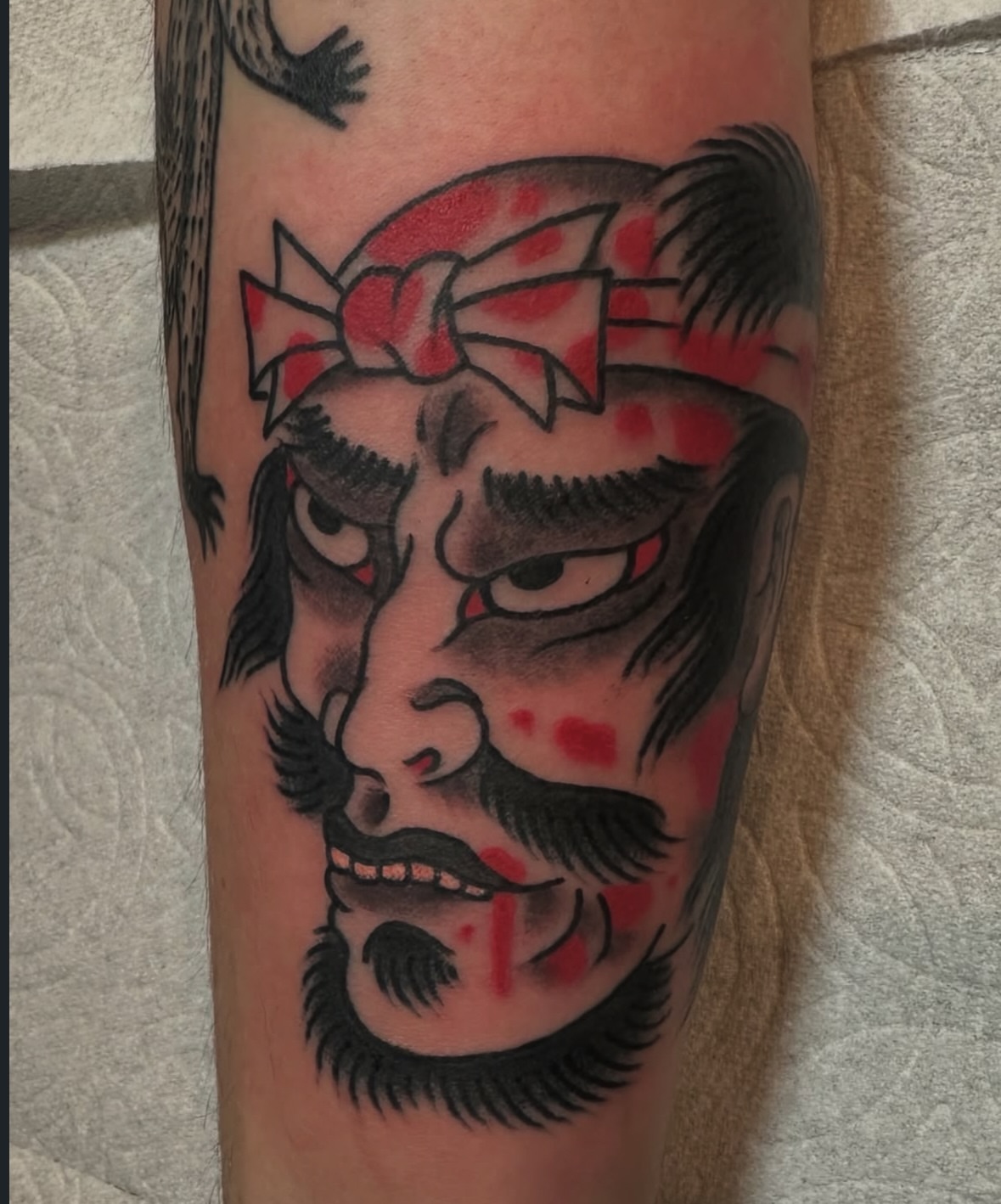 Beast face with bandana American traditional tattoo on the forearm by Daniel Skillingstead
