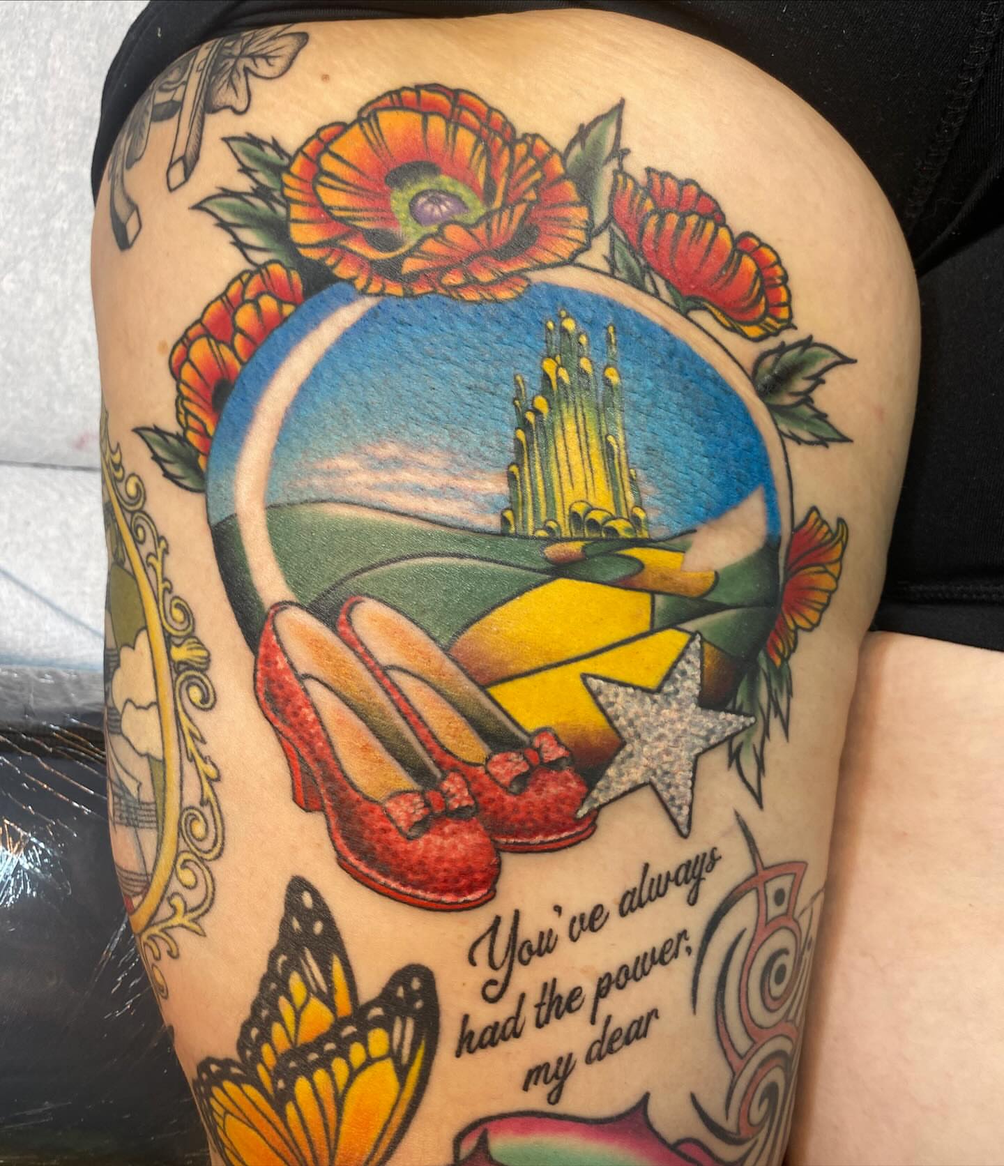 Ruby slippers and wizard of oz landscape American traditional tattoo on the thigh by Vivian HavaTattoo, Richmond, Virginia