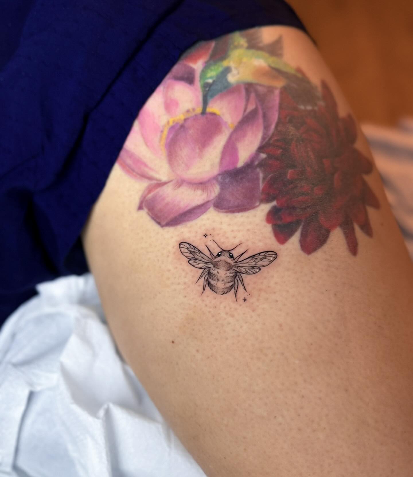 Bee and flowers realism tattoo on the thigh by Whimsical Tattoos