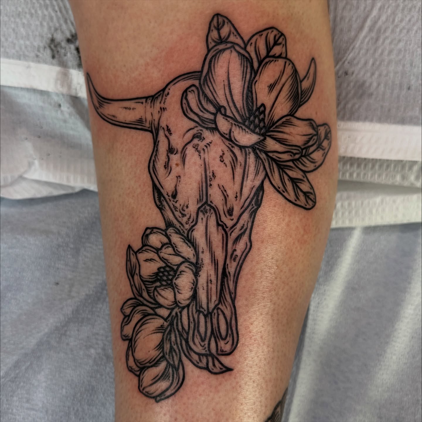 Cow skull with flowers realism tattoo on the forearm by rosalie