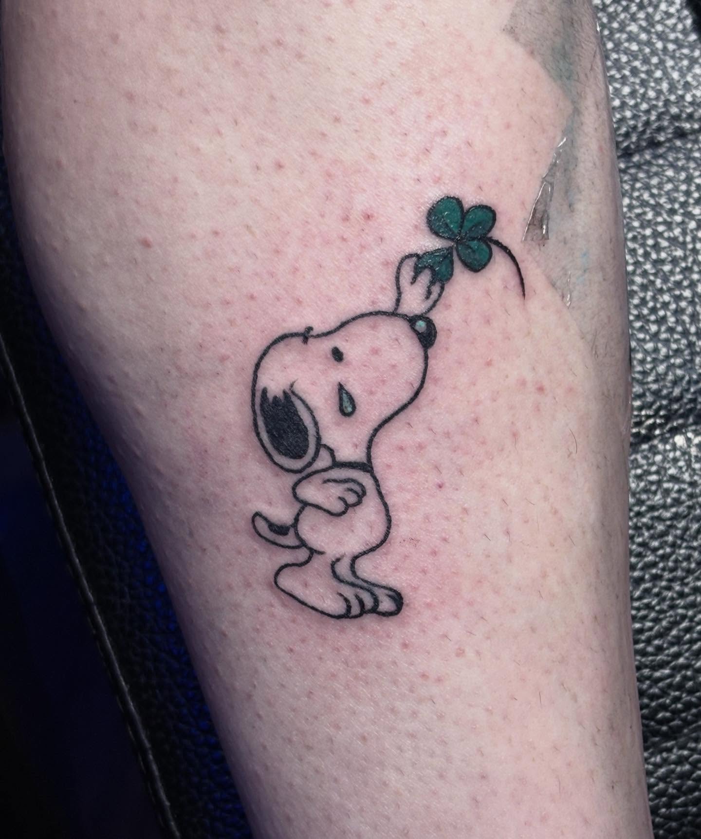 Snoopy holding clover black and grey tattoo on the forearm by Angel Arceo
