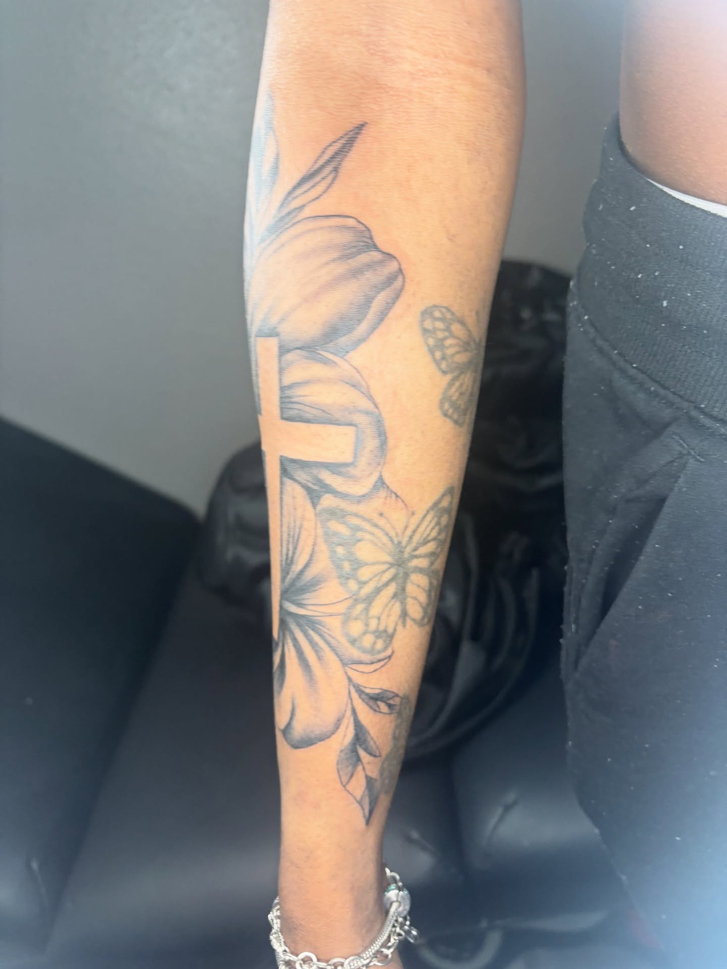 Flowers and butterflies black and grey tattoo on the forearm by Maleek Inkz