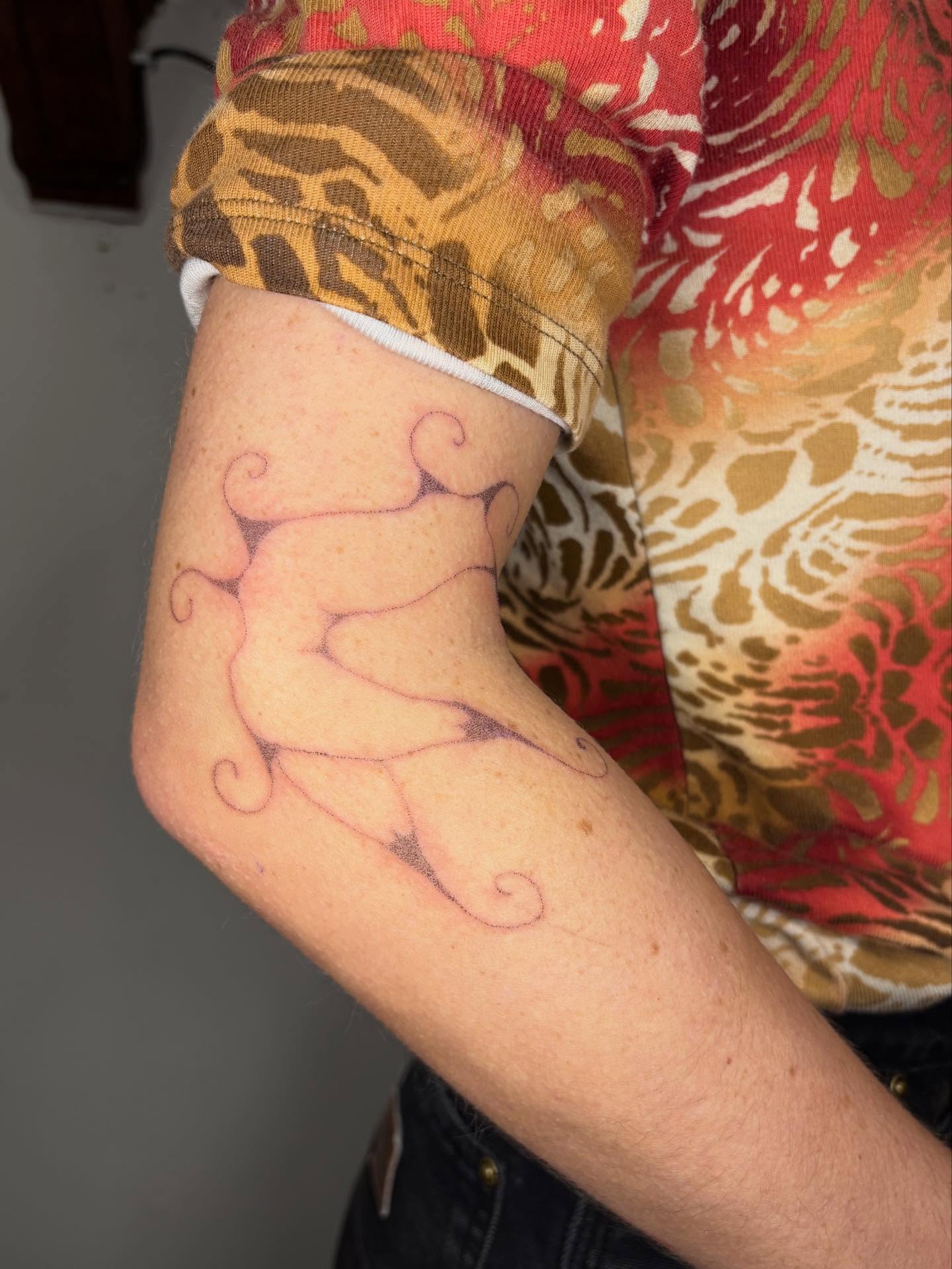 Abstract figure fine line tattoo on the forearm by Jill