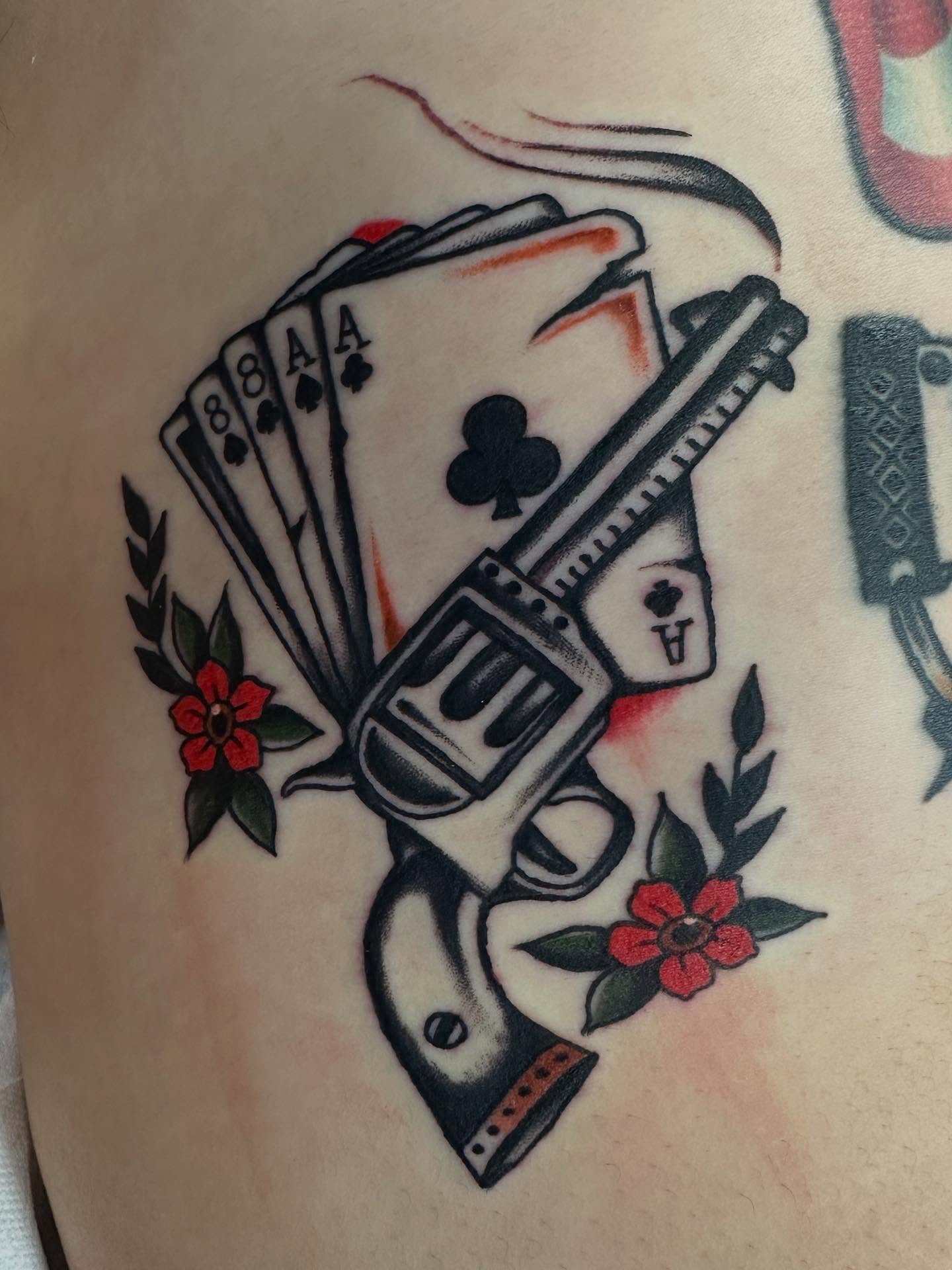 Playing cards and gun American traditional tattoo on the upper arm by David Evans