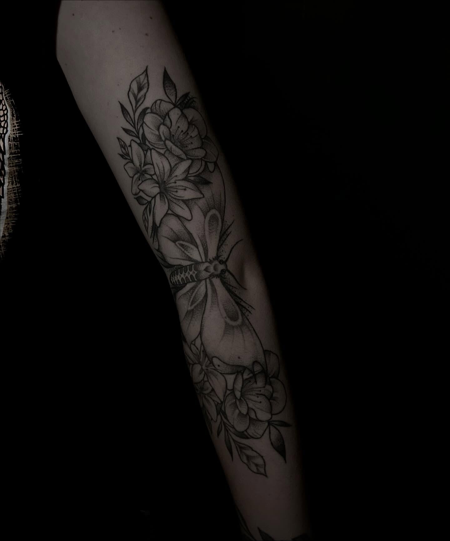 Flowers and moth black and grey tattoo on the forearm by Heaven Arianna