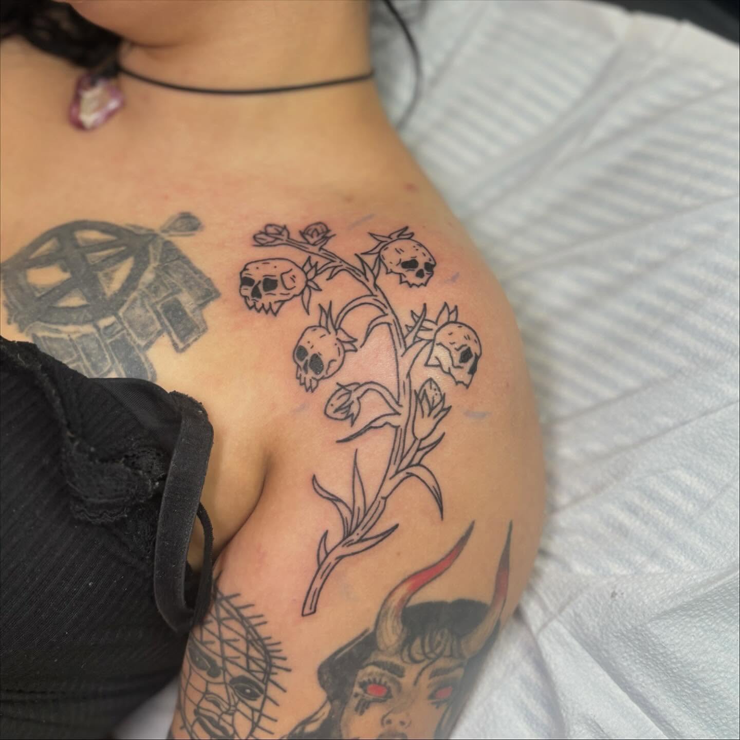 Skulls and flowers black and grey tattoo on the shoulder by Cam Sykes