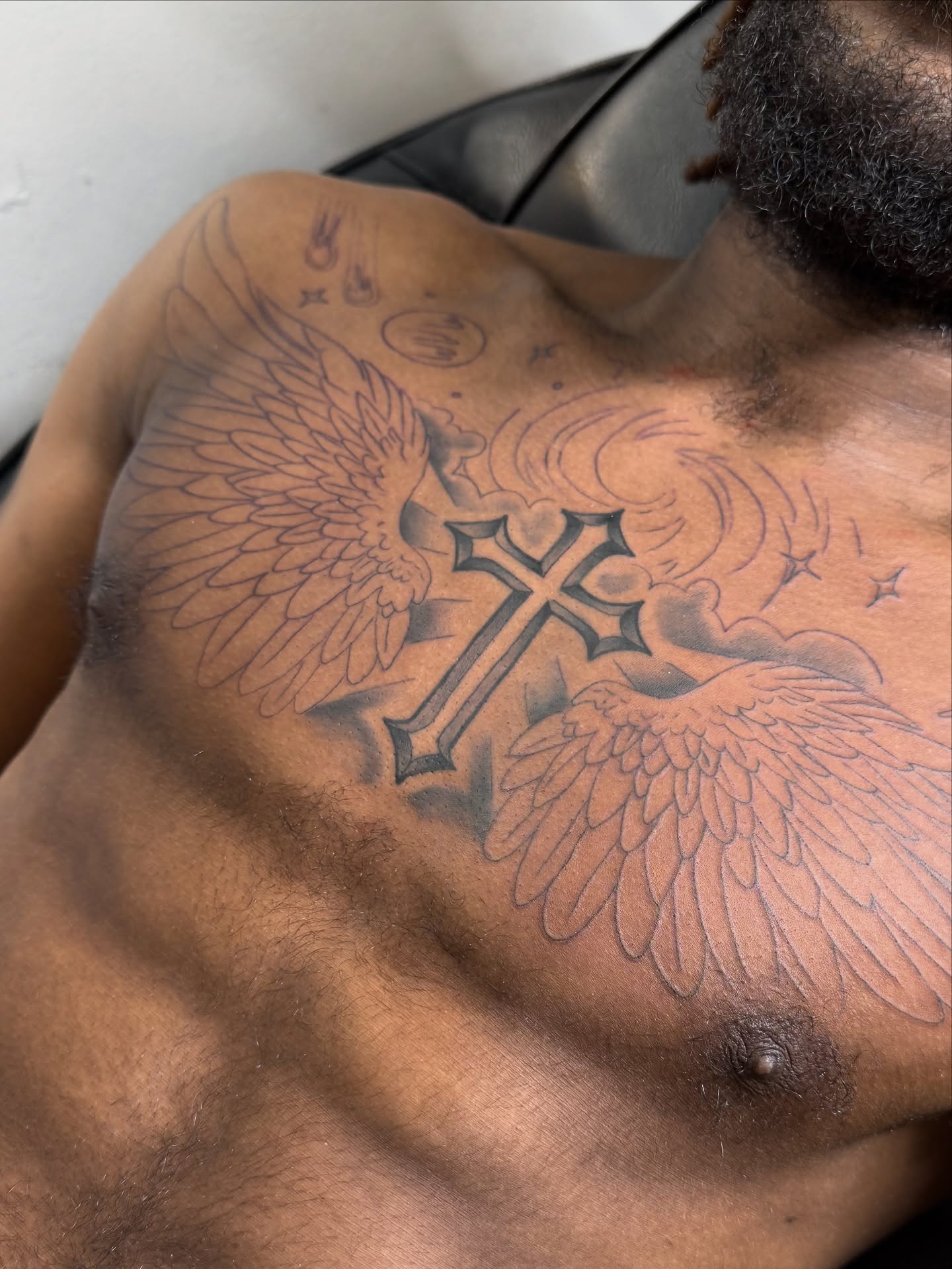 Cross with wings black and grey tattoo on the chest by Eduardo Chaparro
