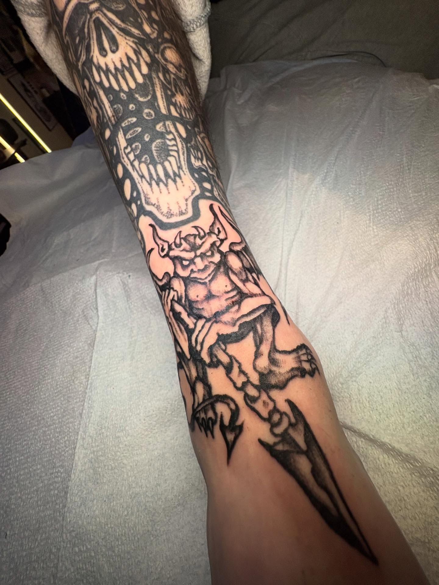 Demon with spear black and grey tattoo on the forearm by Brendan Smith