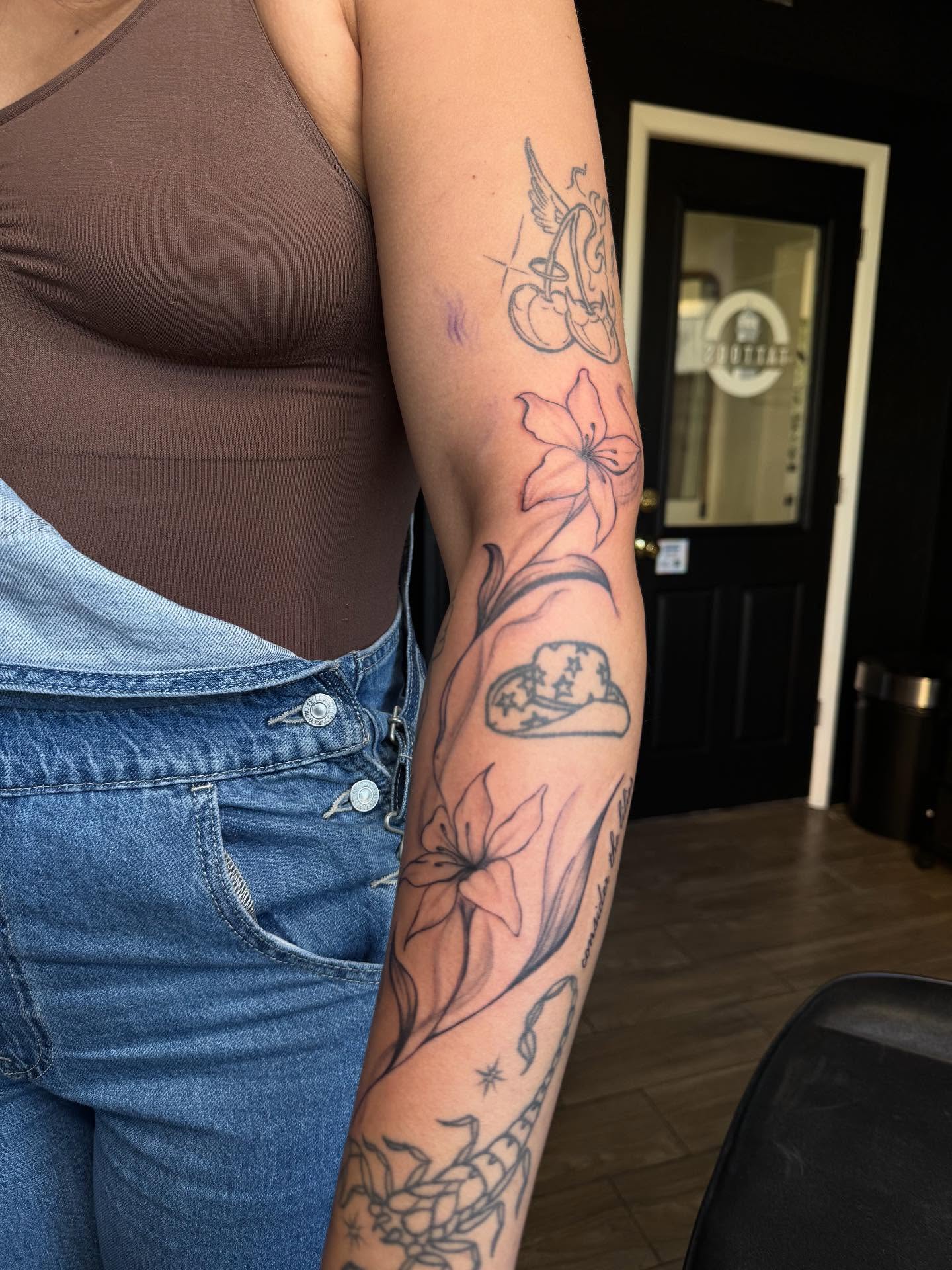 Lilies and stars black and grey tattoo on the forearm by Mickey