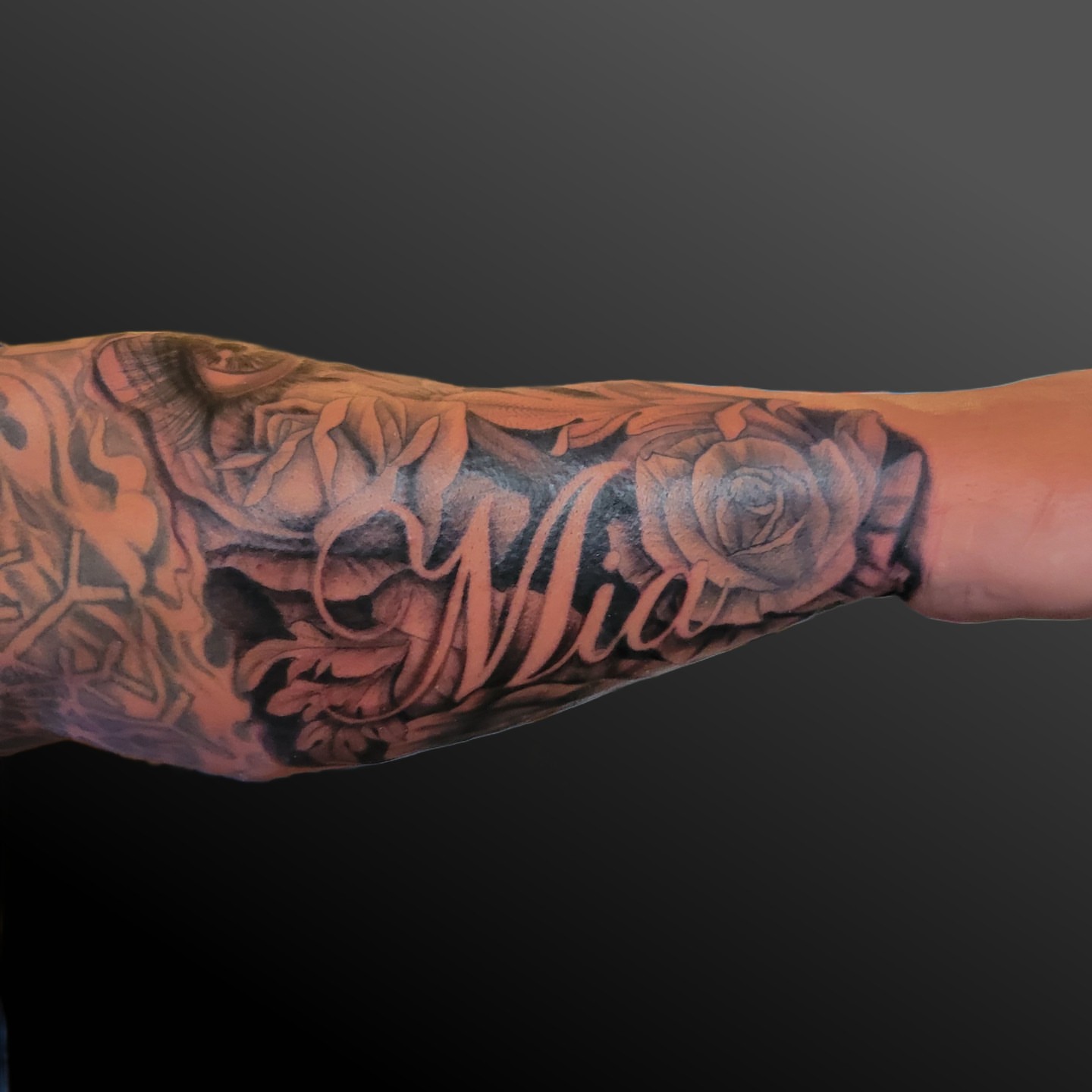 Roses and name black and grey tattoo on the forearm by Arick Reese