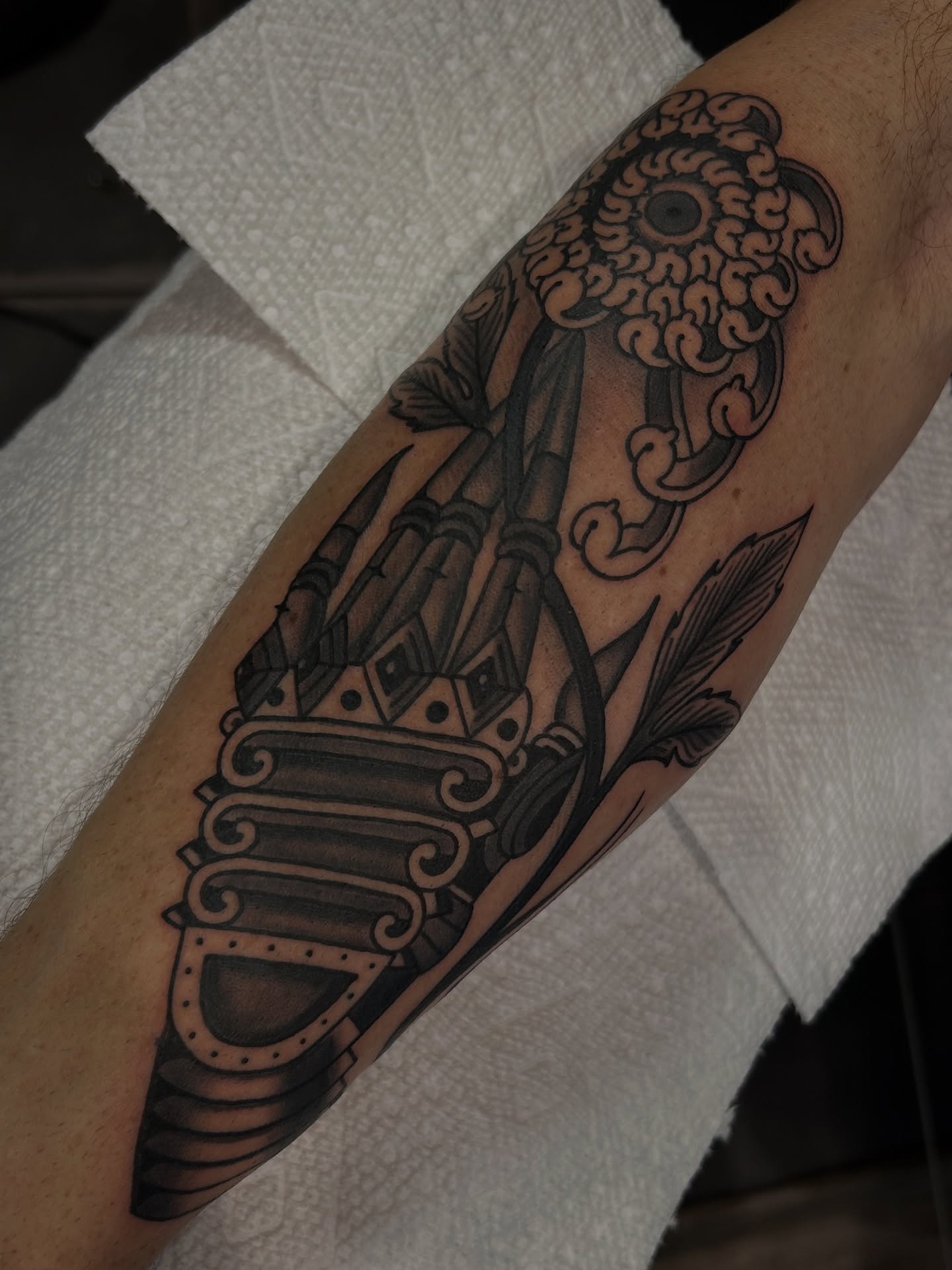 Key and floral design black and grey tattoo on the forearm by Lilly Binns