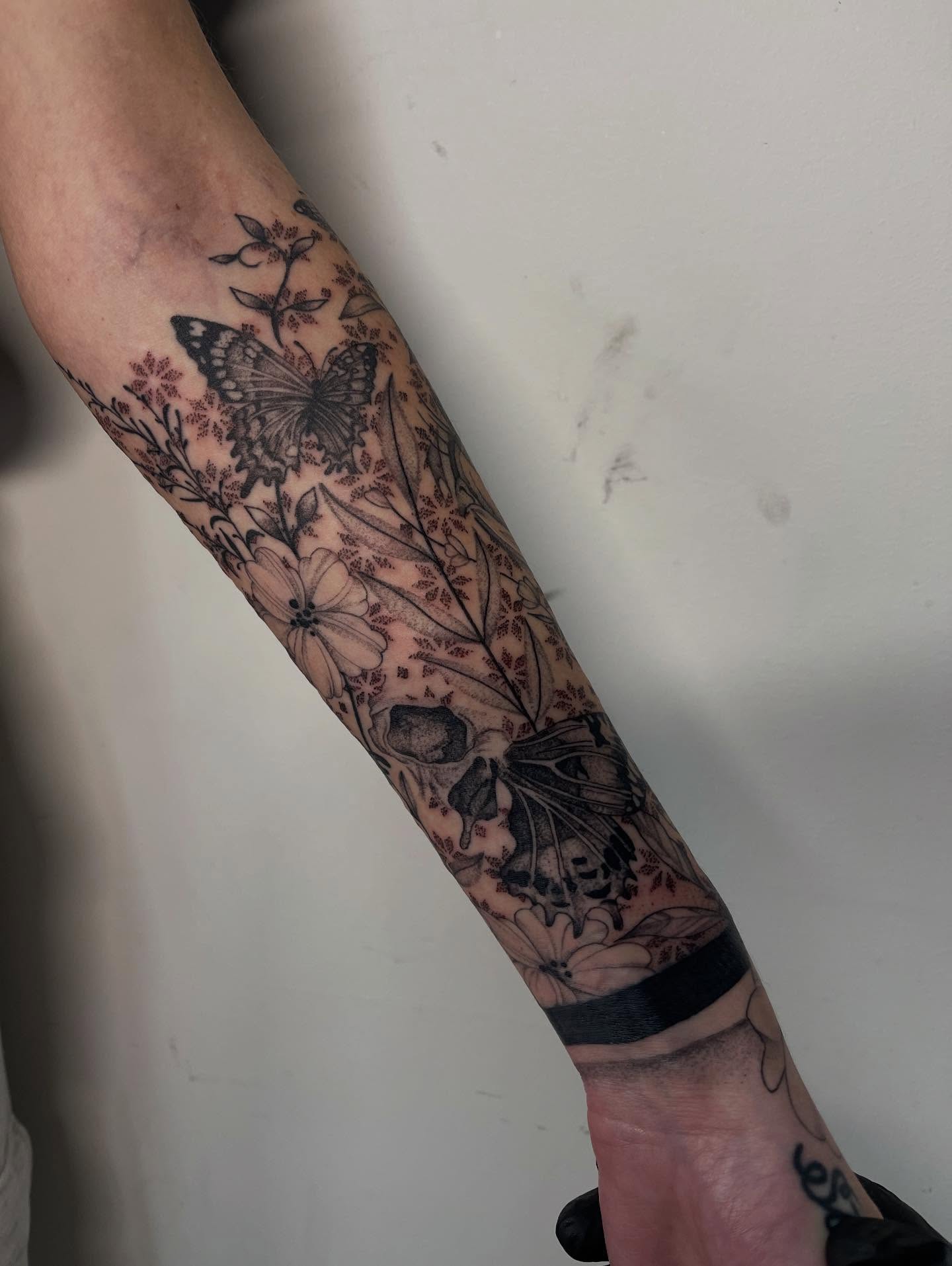 Butterfly and floral black and grey tattoo on the forearm by Miesha Busker