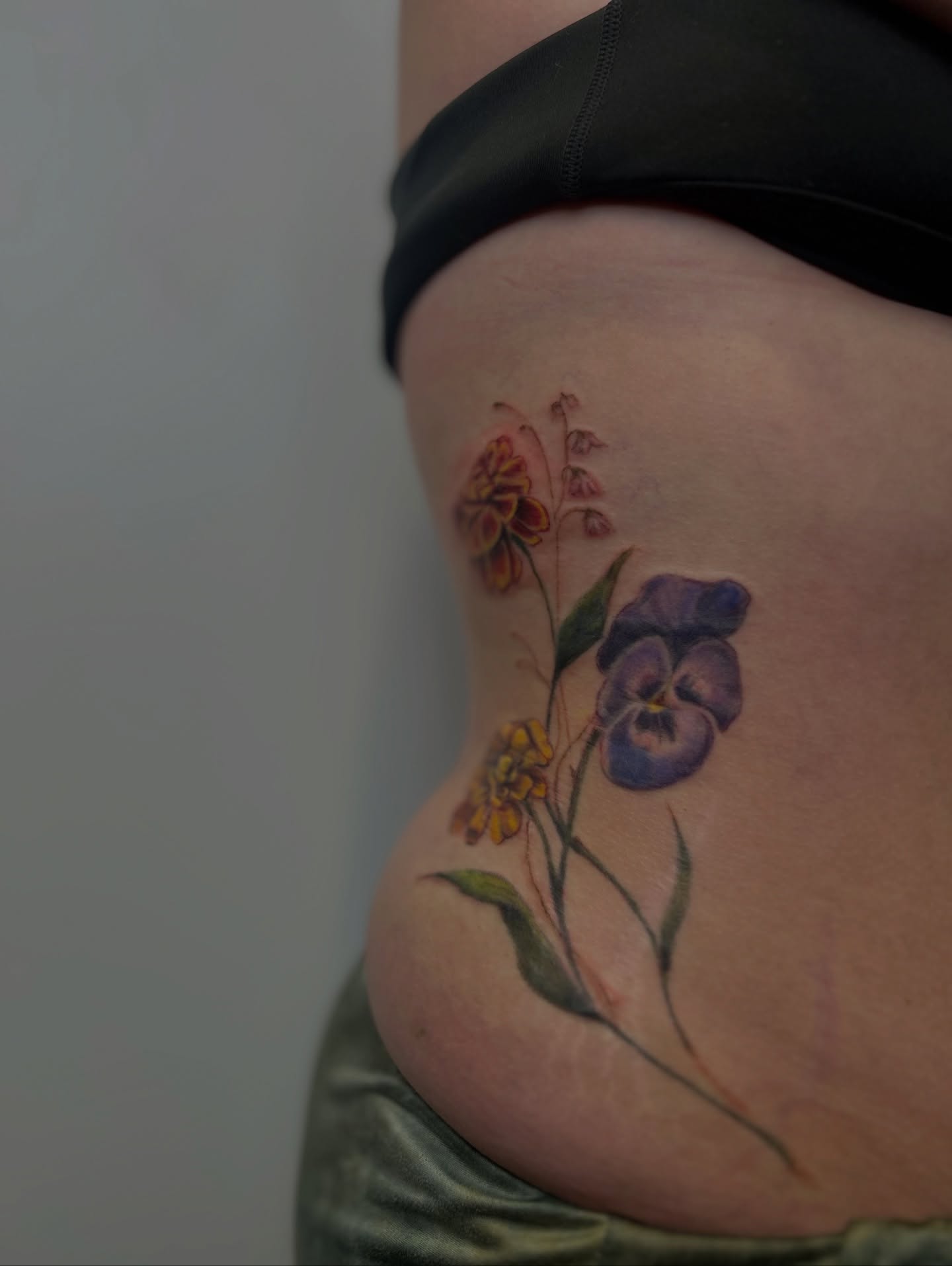 Floral arrangement watercolor tattoo on the ribs by Mackenzie