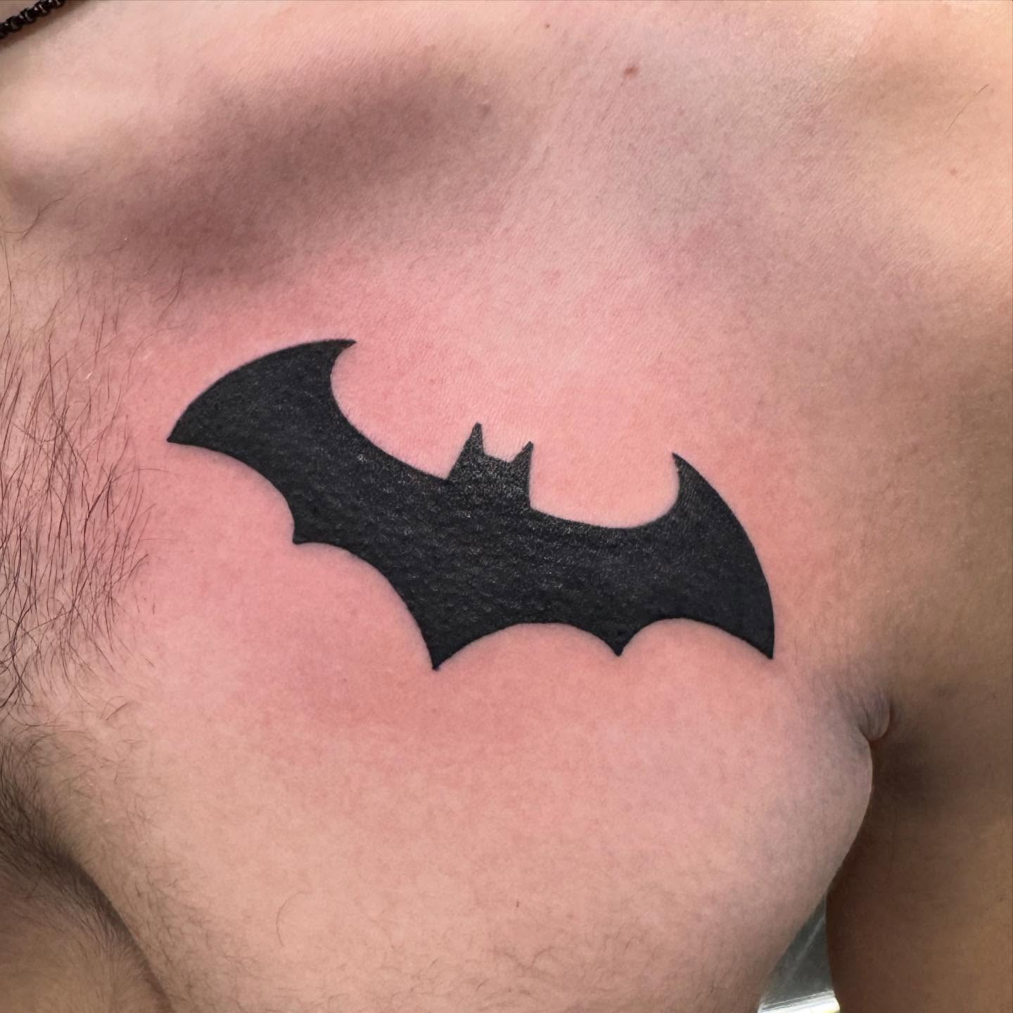 Bat symbol black and grey tattoo on the chest by Brian Herrera