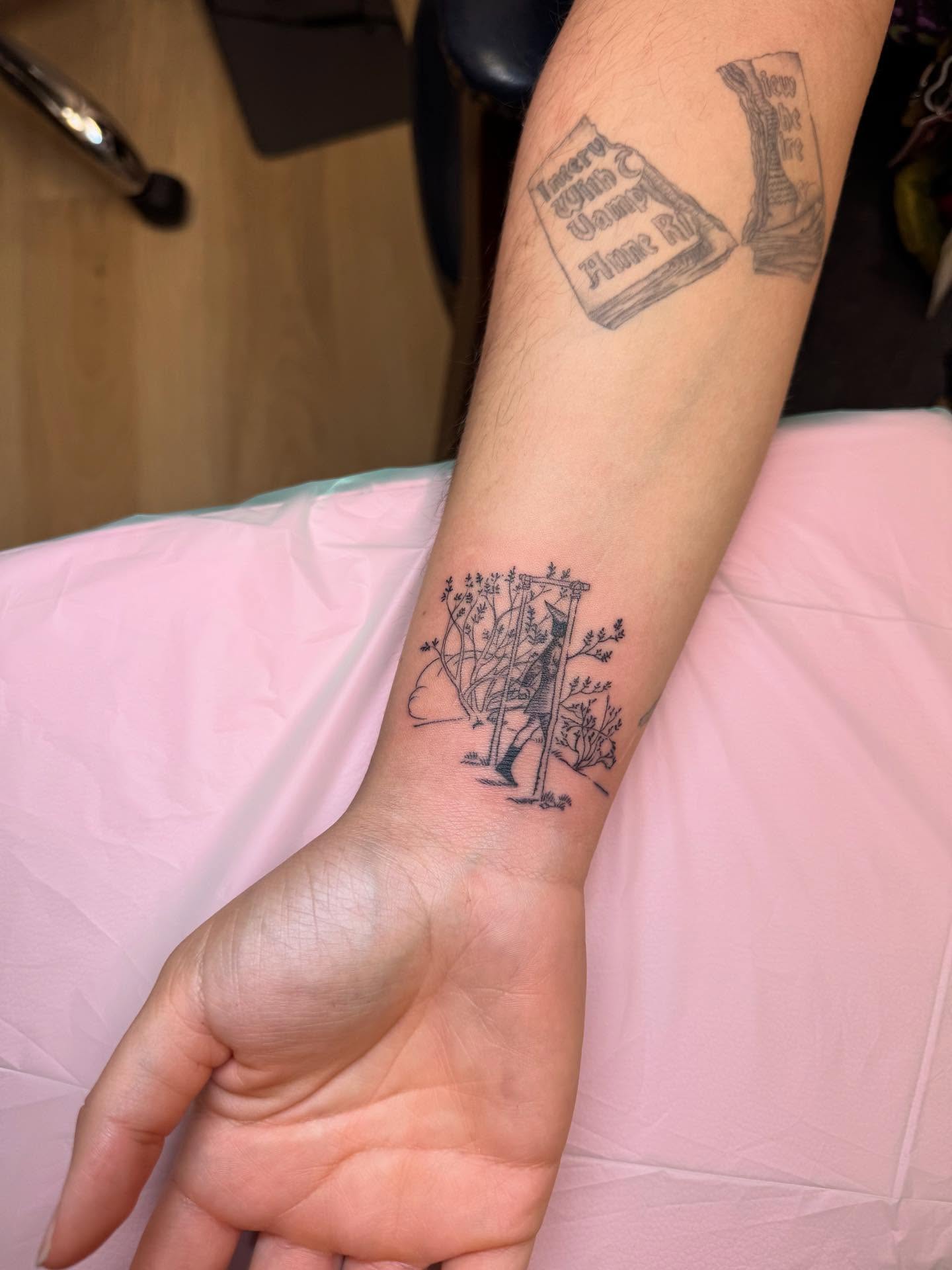 Book and plant black and grey tattoo on the forearm by Maddie Hammell