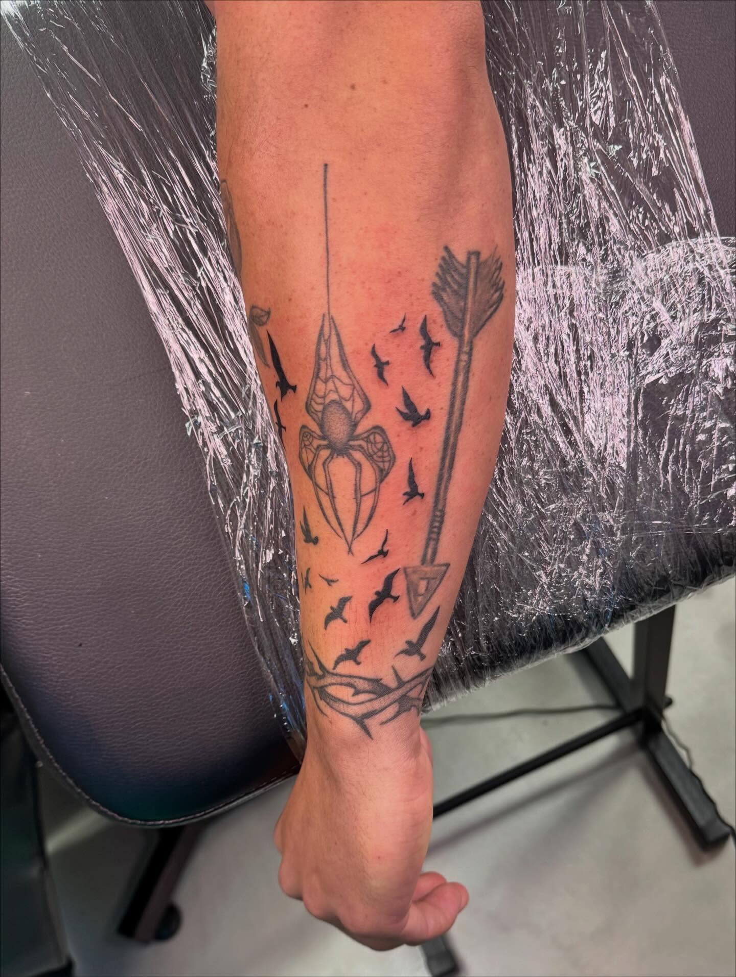 Spider and arrow black and grey tattoo on the forearm by haylie