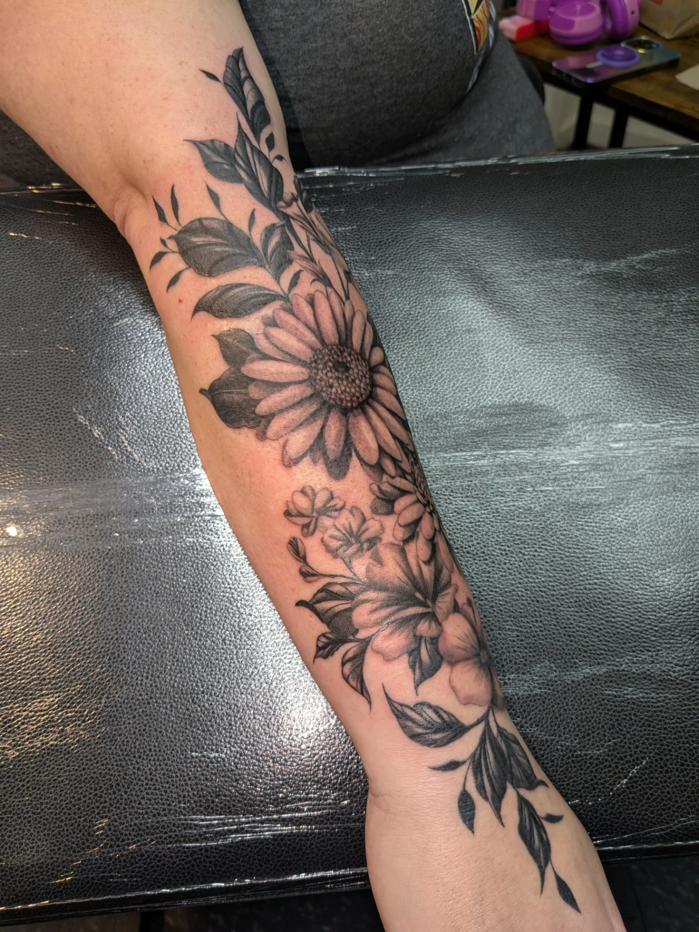 Sunflower and floral arrangement black and grey tattoo on the forearm by Jessica Thomas Fleischman, Morganton, North Carolina