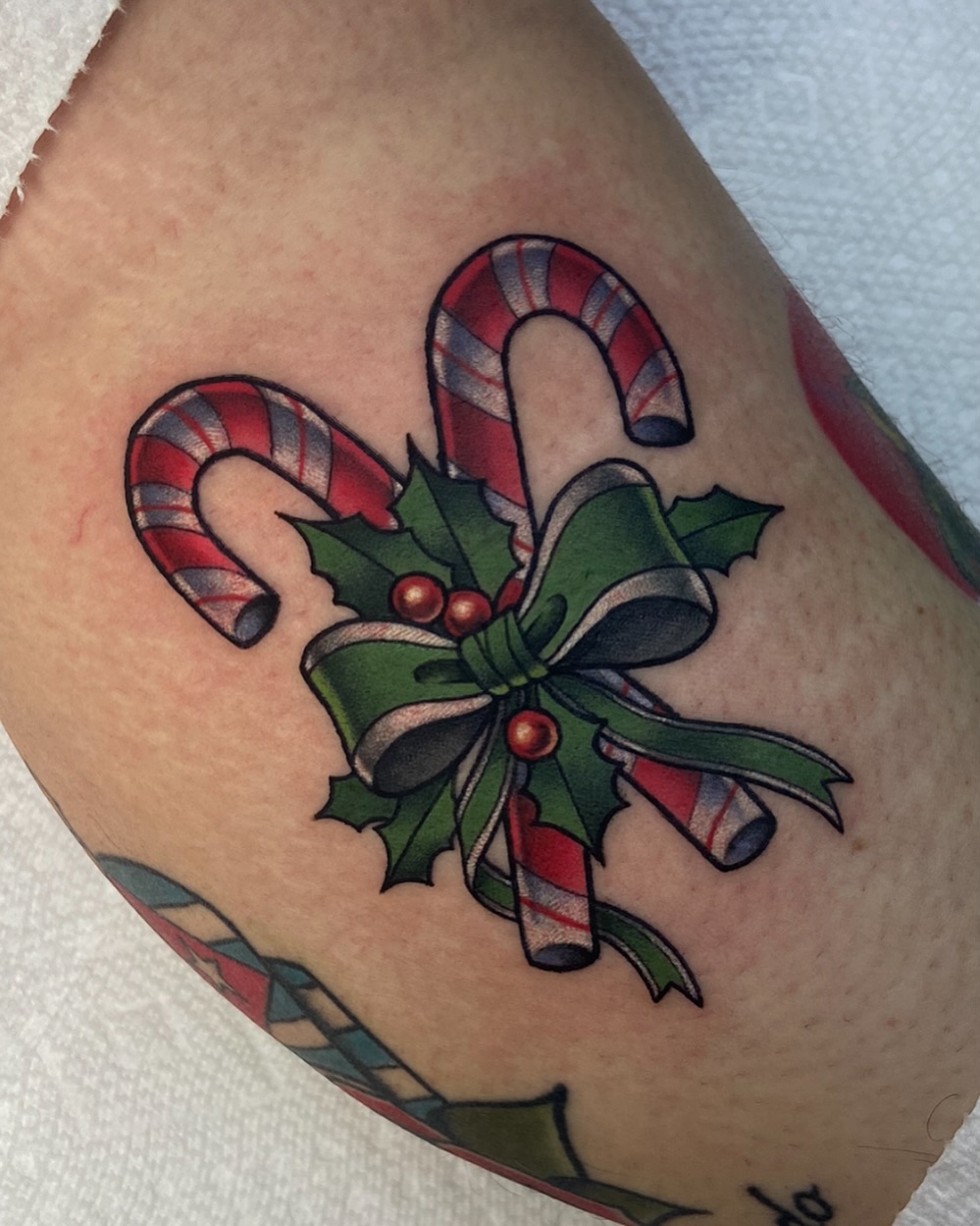 Candy canes and holly American traditional tattoo on the forearm by ππππππ