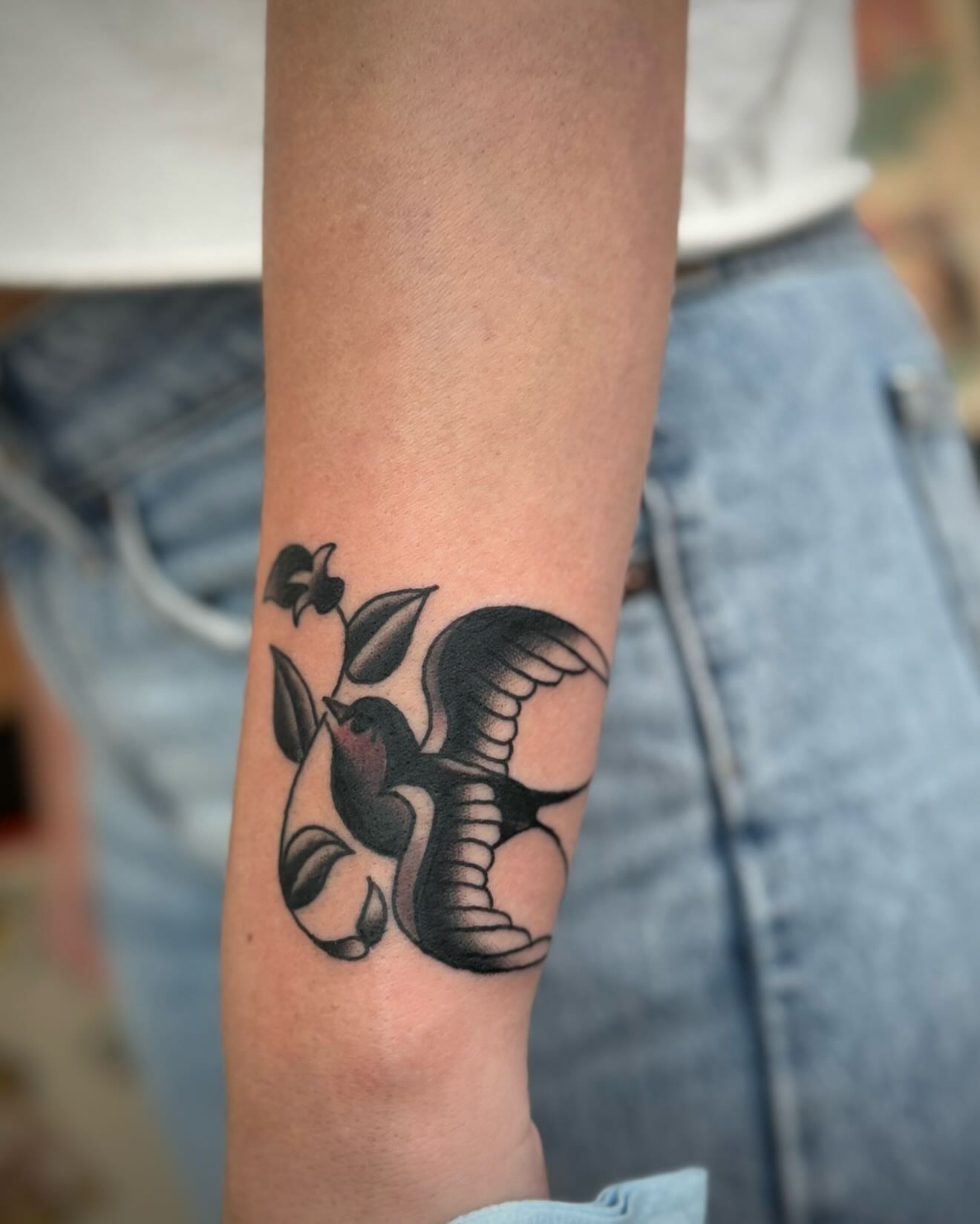 Bird and flower black and grey tattoo on the forearm by kalli berry