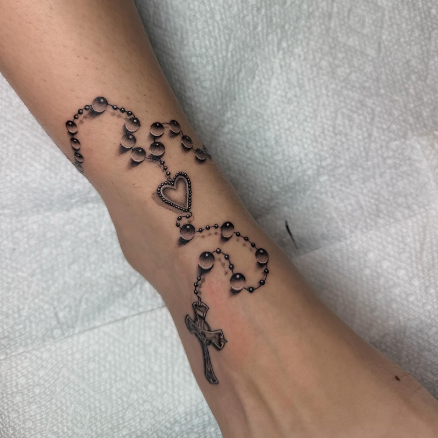 Rosary black and grey tattoo on the forearm by Jas Knight