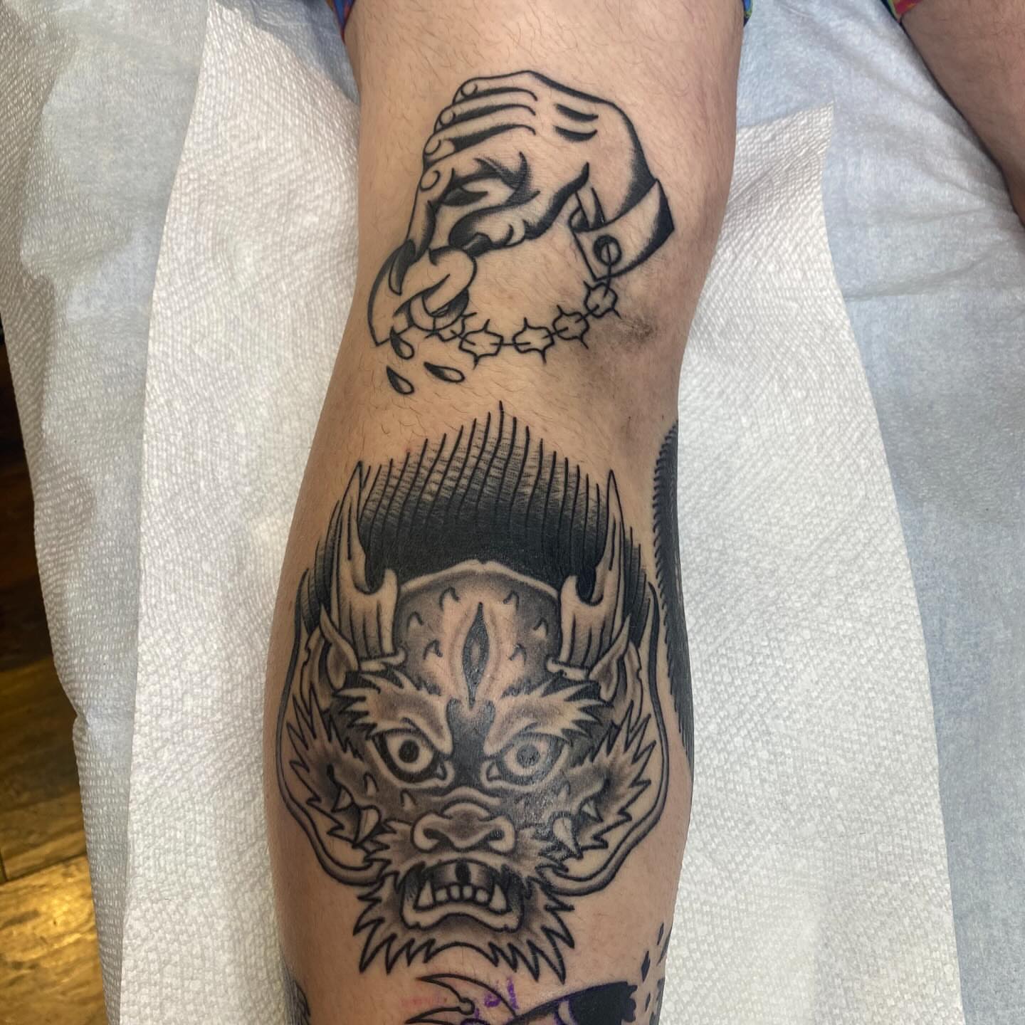 Demon head black and grey tattoo on the forearm by Thomas Cook