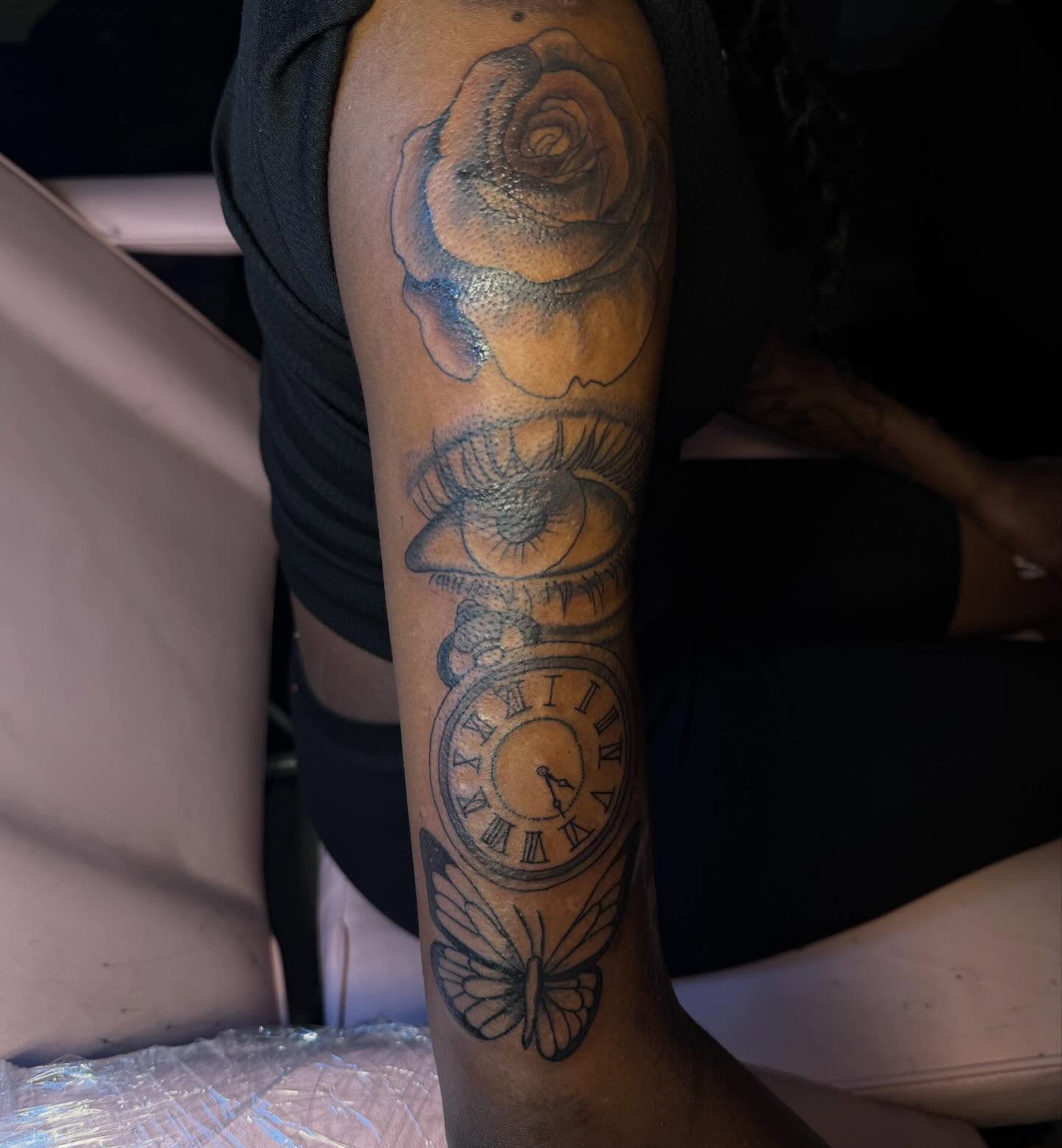 Rose, eye, clock, butterfly realism tattoo on the forearm by Tatted By Layy