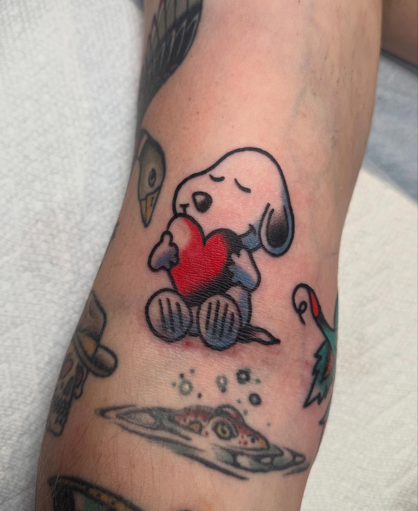Snoopy holding heart American traditional tattoo on the forearm by Elle Yax