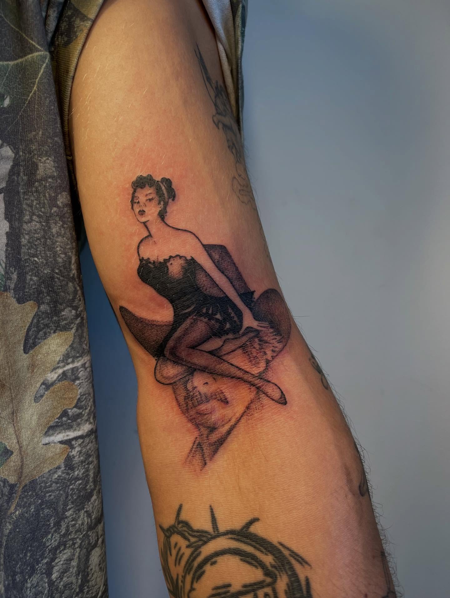 Pin-up girl black and grey tattoo on the forearm by Miesha Busker