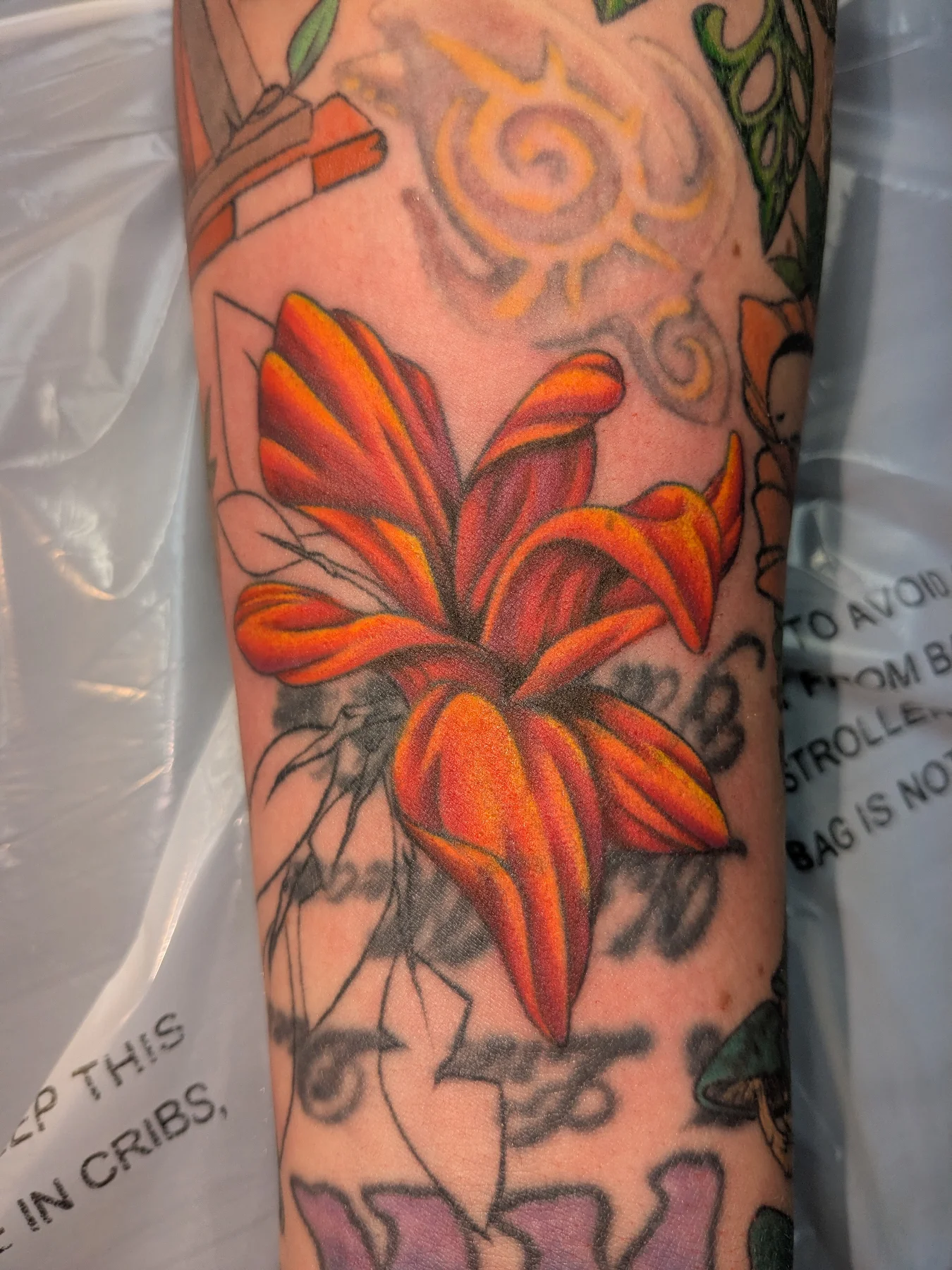 Orange lily realism tattoo on the forearm by Jessica Thomas Fleischman, Morganton, North Carolina