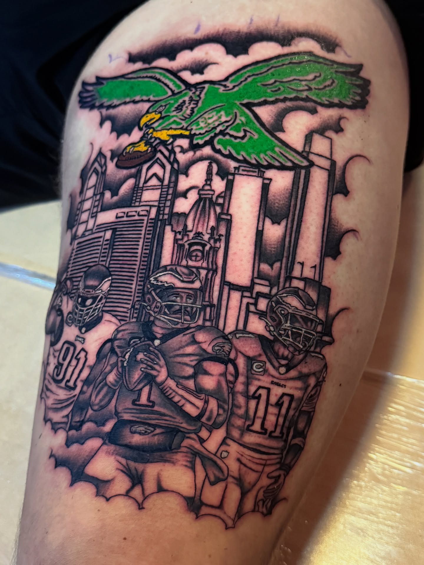 Football players and eagle American traditional tattoo on the thigh by Angus Perfect, Philadelphia, Pennsylvania