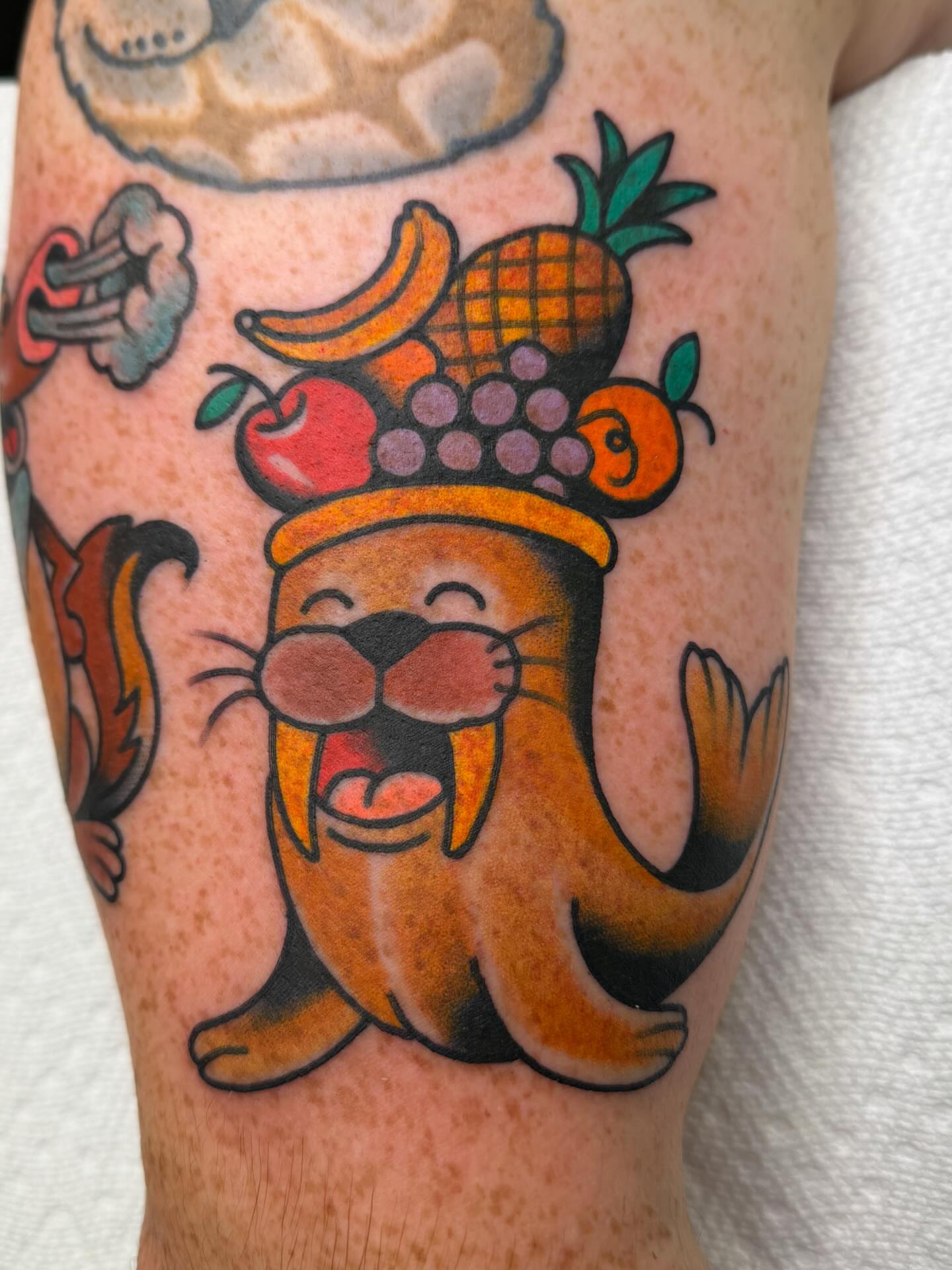 Otter with fruit crown American traditional tattoo on the forearm by Danny Reed, Asheville, North Carolina