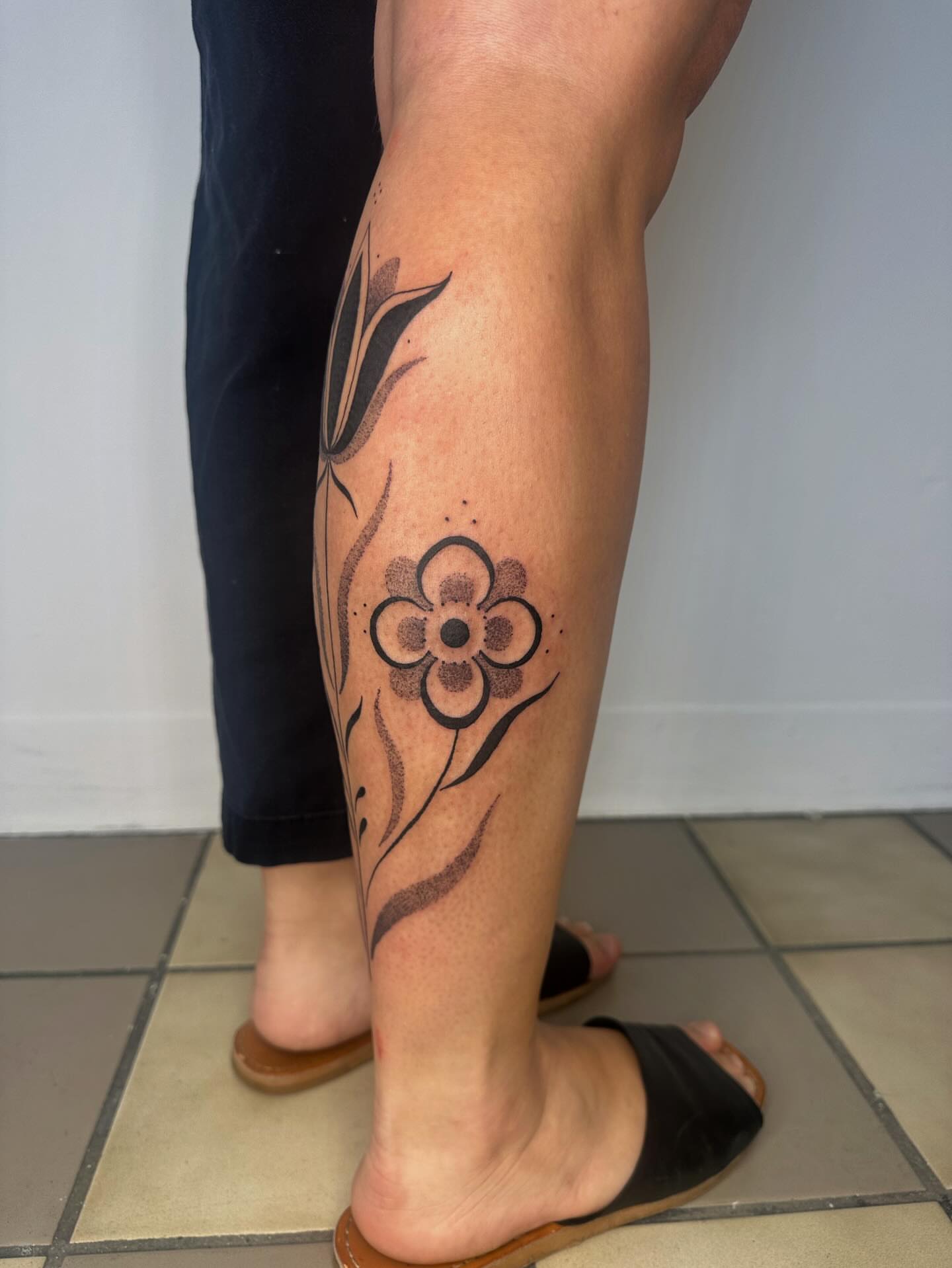 Flower dotwork tattoo on the calf by J Valentin