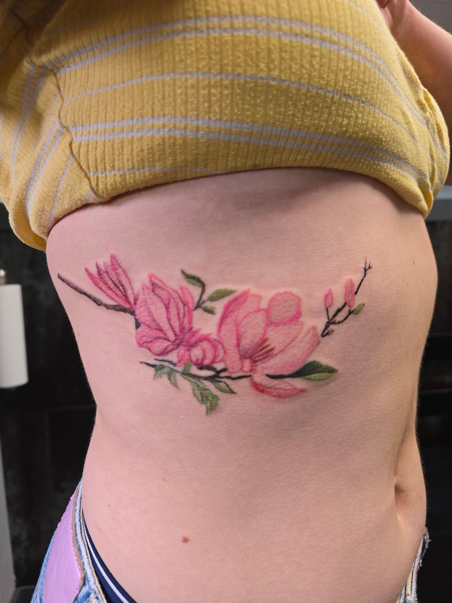 Magnolia blossoms watercolor tattoo on the ribs by Karen Cain