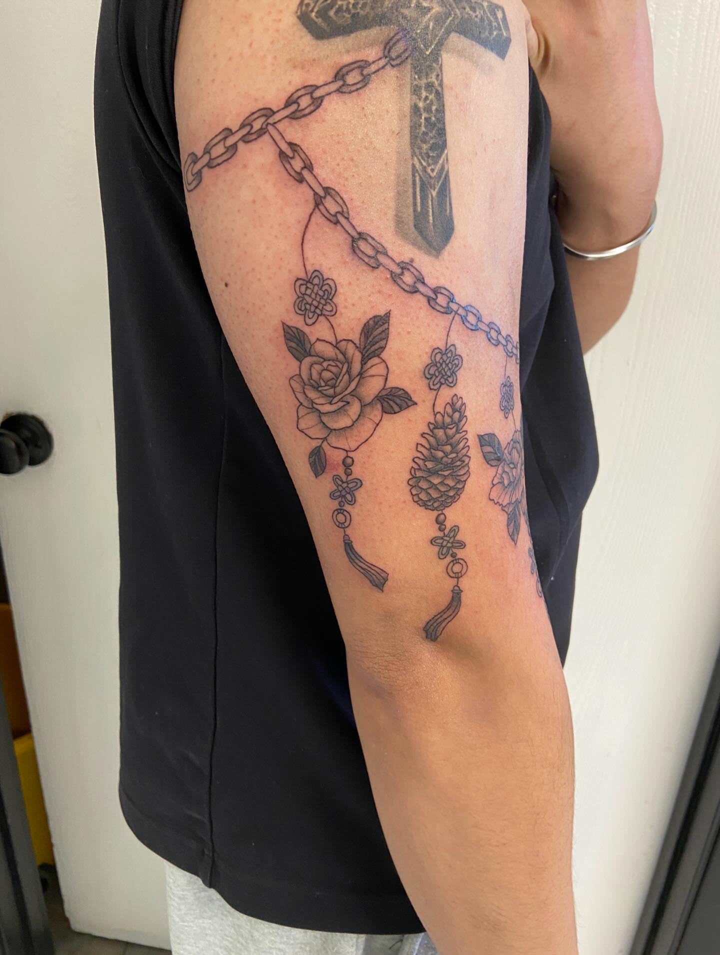 Cross and chain black and grey tattoo on the forearm by Sophia