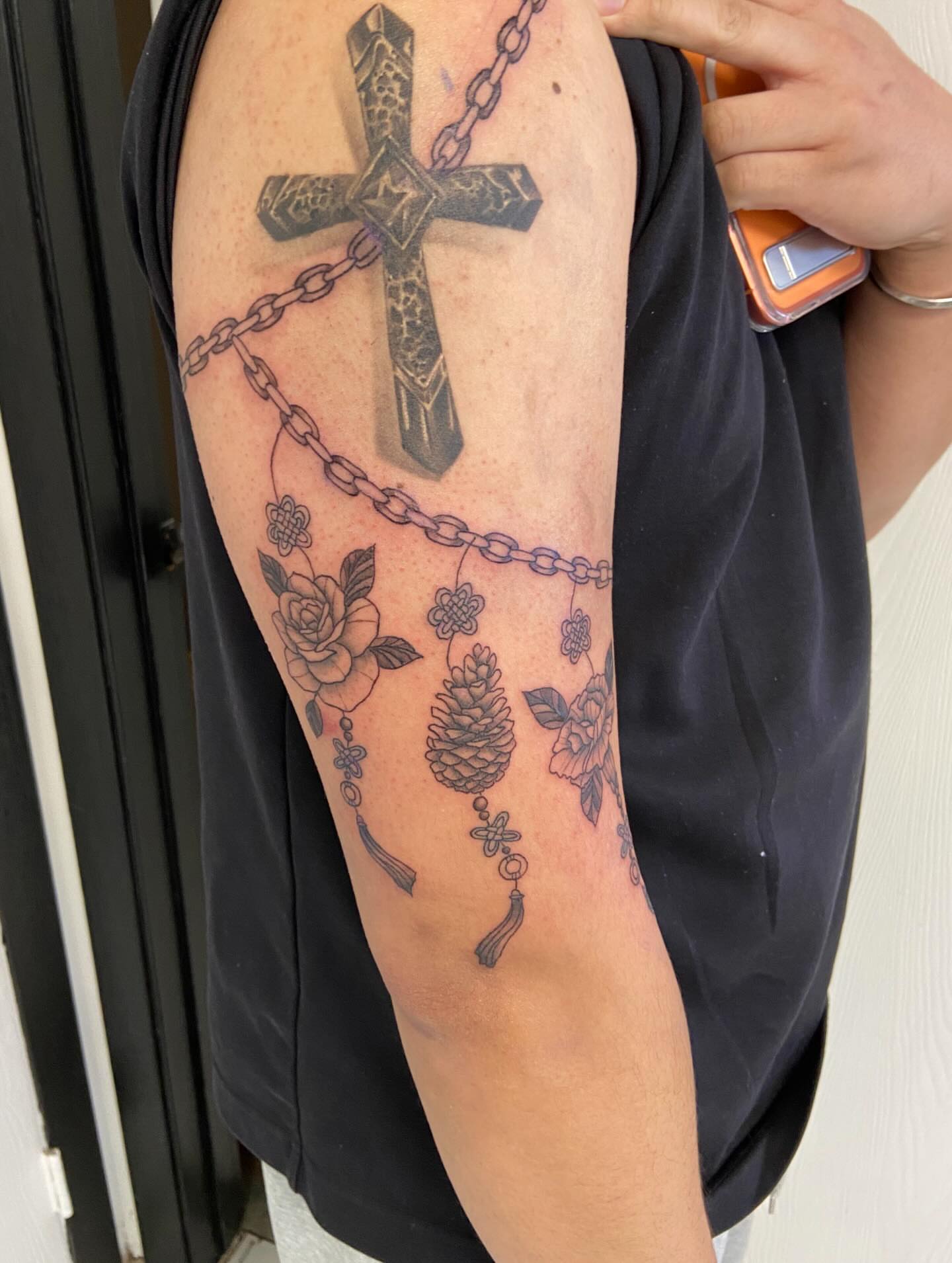 Cross and floral black and grey tattoo on the forearm by Sophia