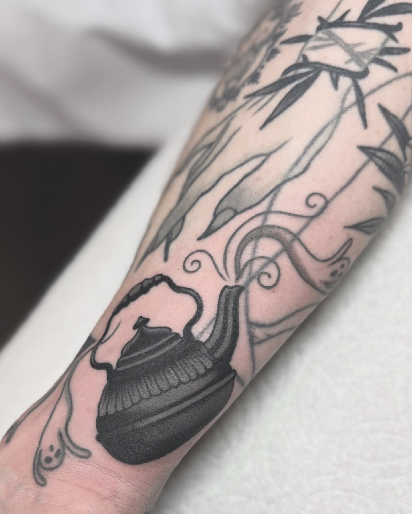 Teapot and bamboo black and grey tattoo on the forearm by Nia (Knee-uhh) 🦷