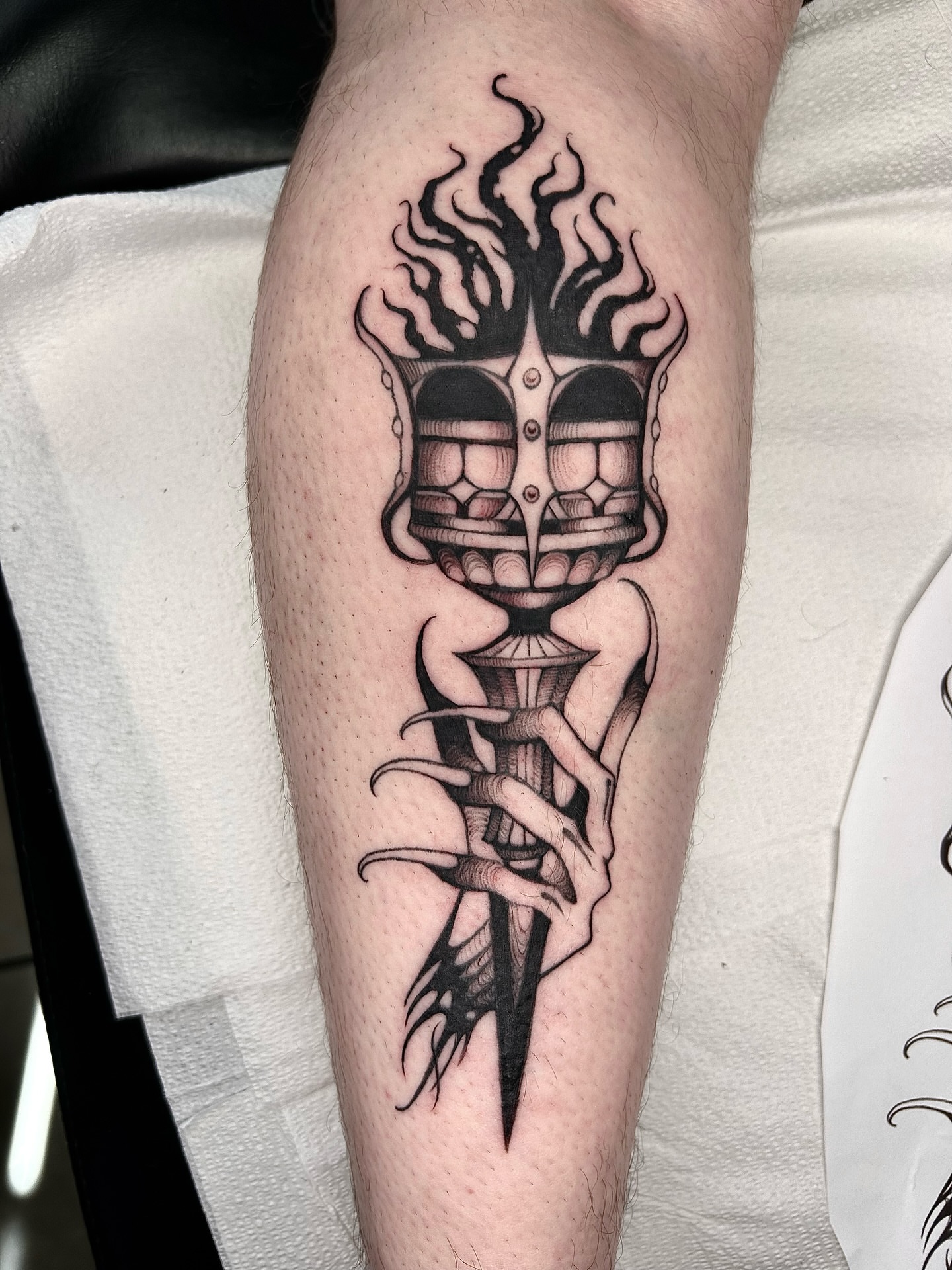 Mask with flames black and grey tattoo on the forearm by Magnus