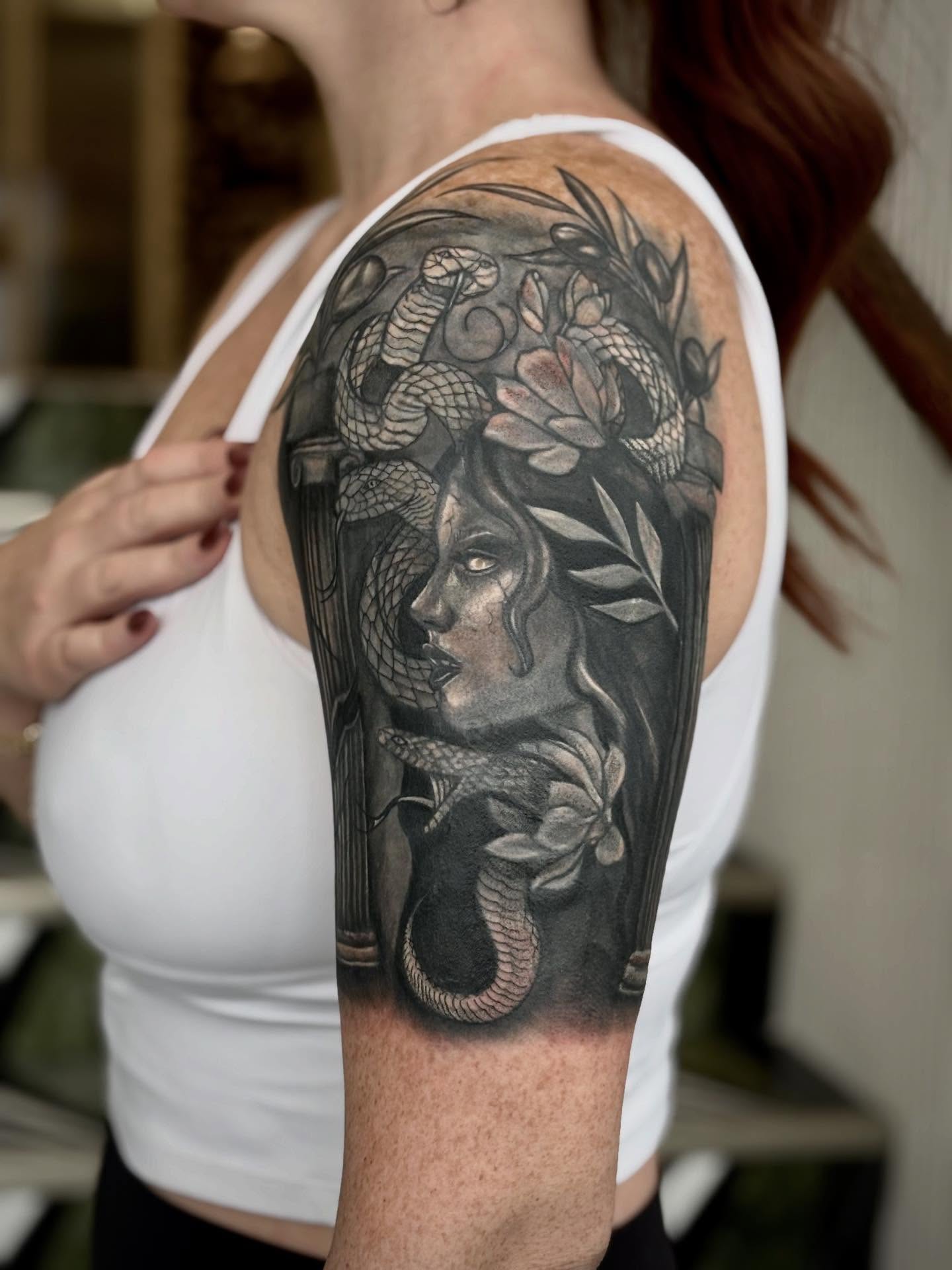 Woman with snakes realism tattoo on the upper arm by Jazzlyn Hous