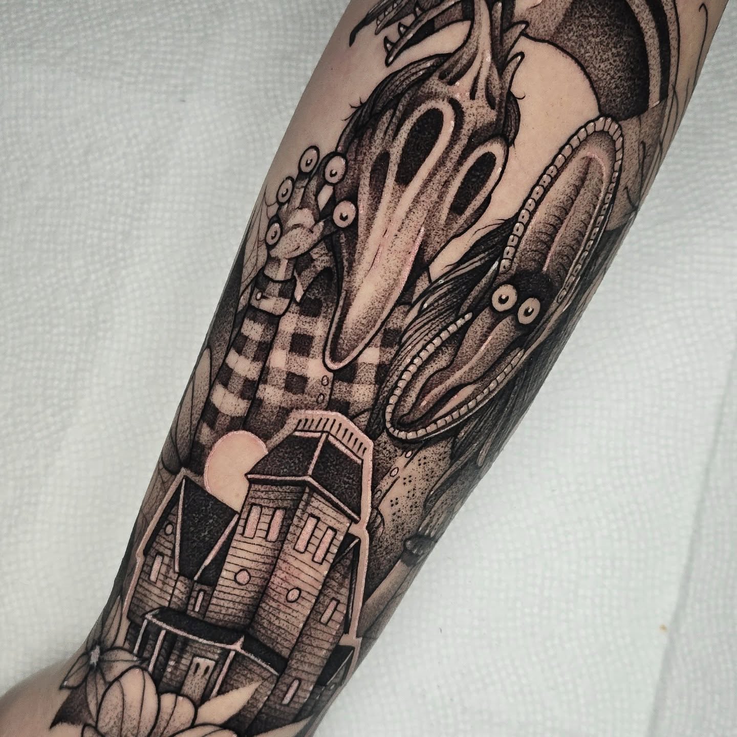 Monster and town dotwork tattoo on the forearm by Justin Eldridge