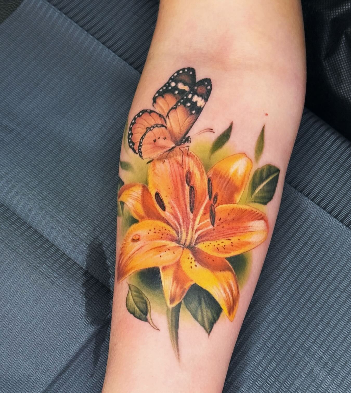 Lily and butterfly realism tattoo on the forearm by Eric Axle