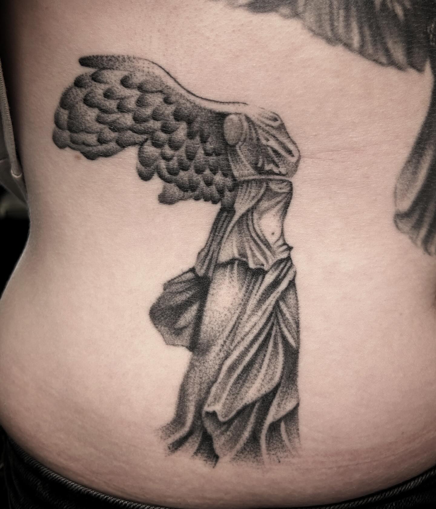 Statue with wings black and grey tattoo on the torso by Kayla Shoffner