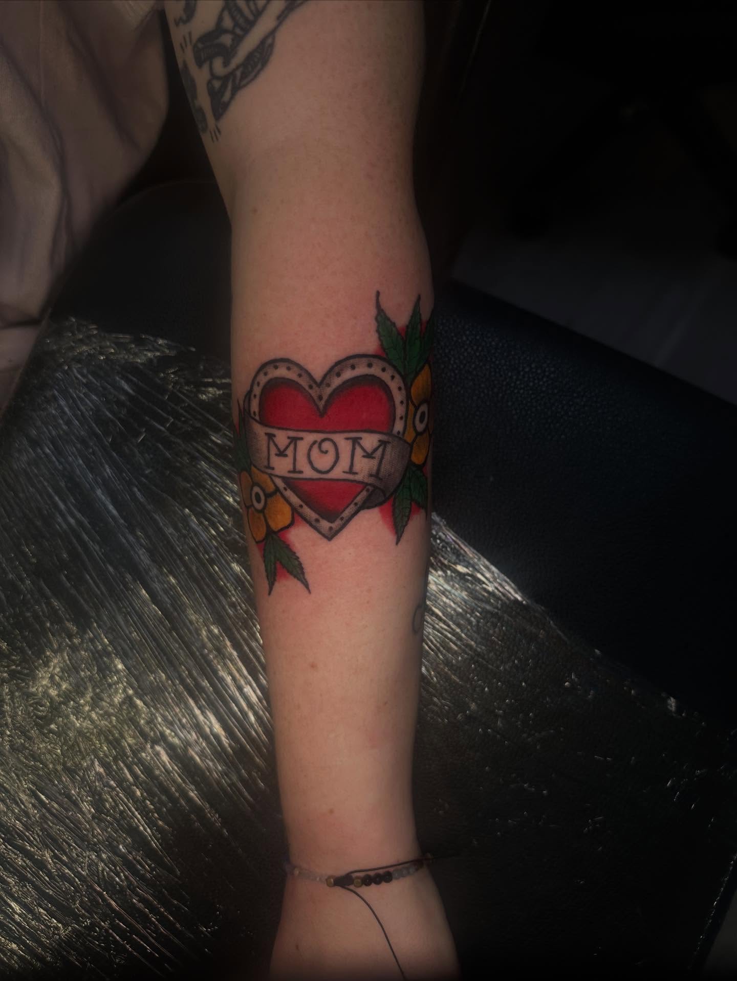 Heart with 'mom' American traditional tattoo on the forearm by Aj Negrete Jr.