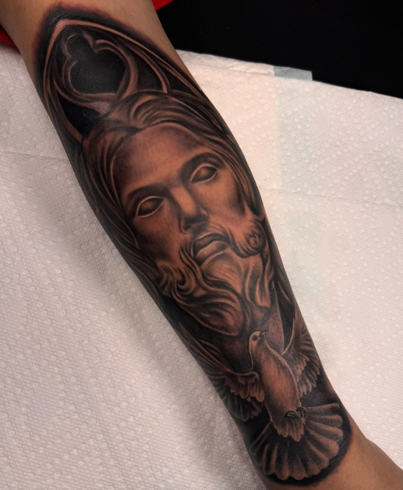 Religious figure with dove realism tattoo on the forearm by Elijah East