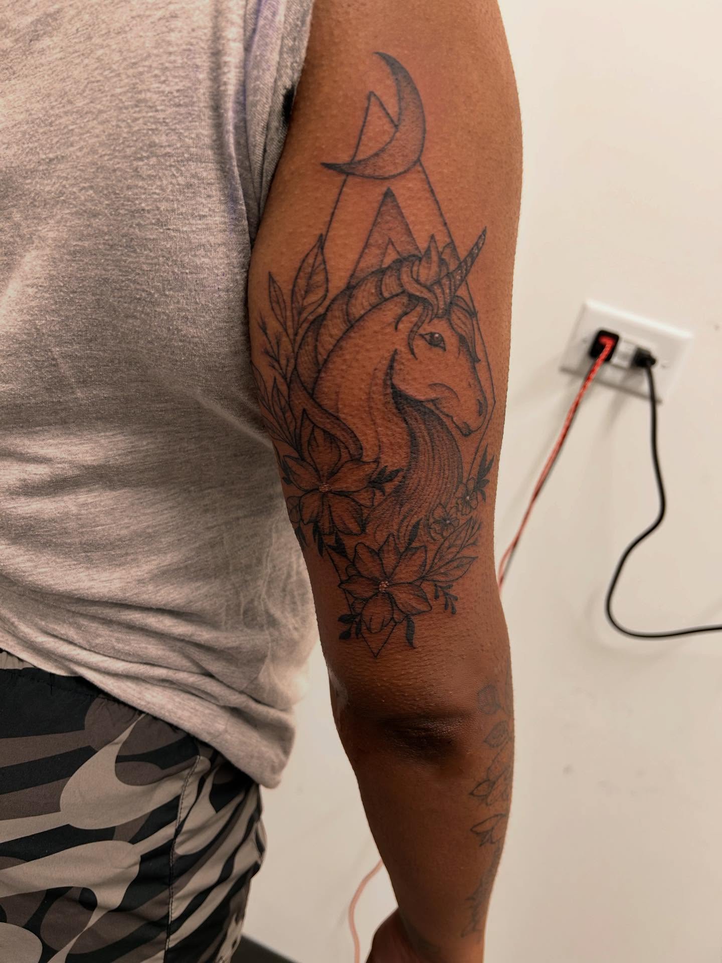 Unicorn and flowers black and grey tattoo on the forearm by Stephania ATLANTA TATTOO ARTIST🎨